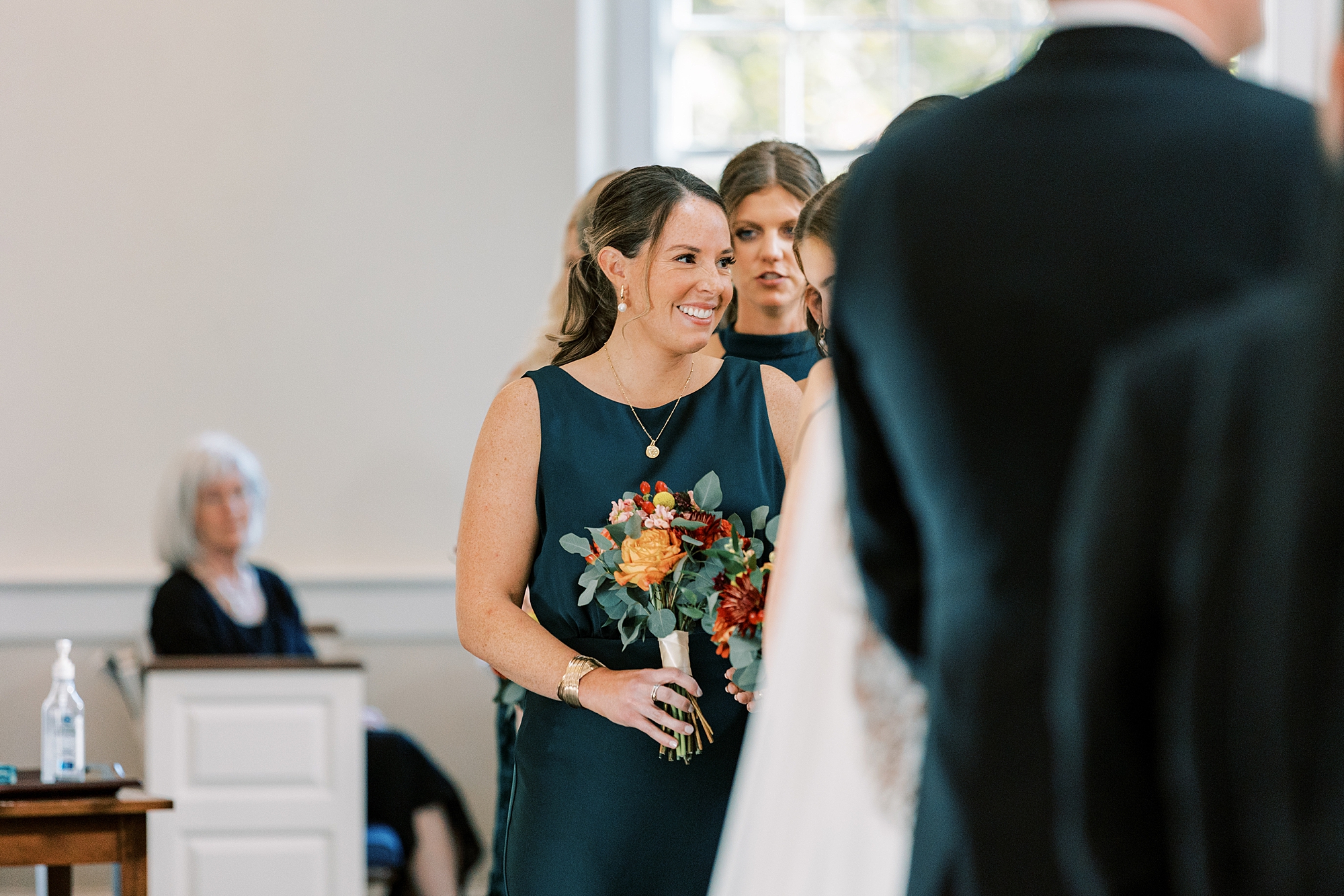 bridesmaid in teal dress holds fall bouquet inside St. David’s Episcopal Church 