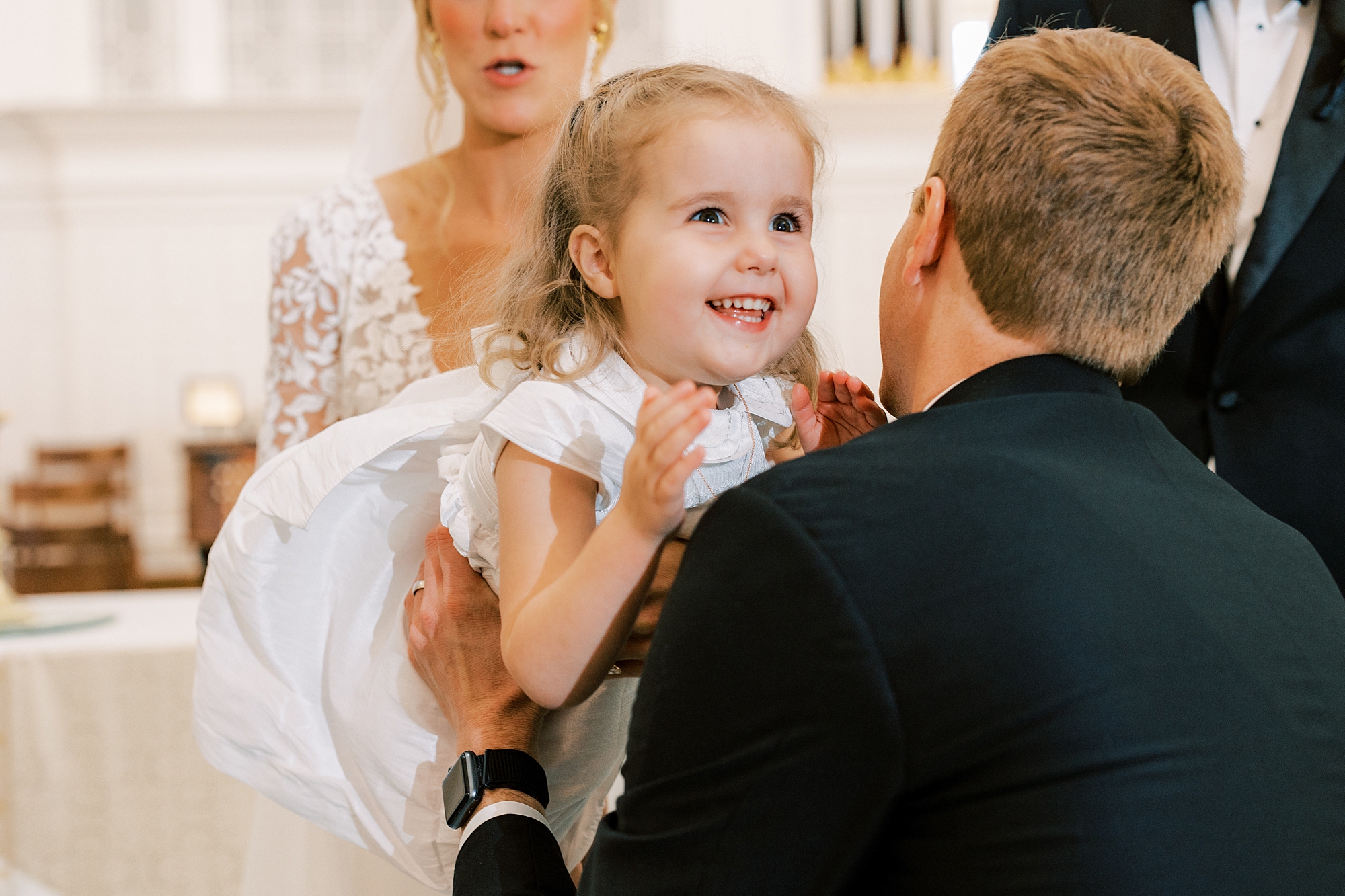 flower girl laughs with dad leaving bride's arms 