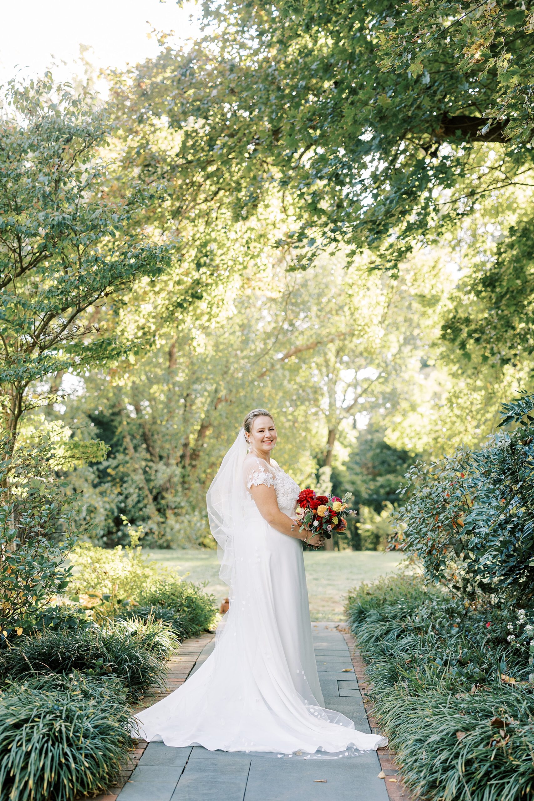 bride looks over shoulder holding pink and orange bouquet at Greenville Country Club