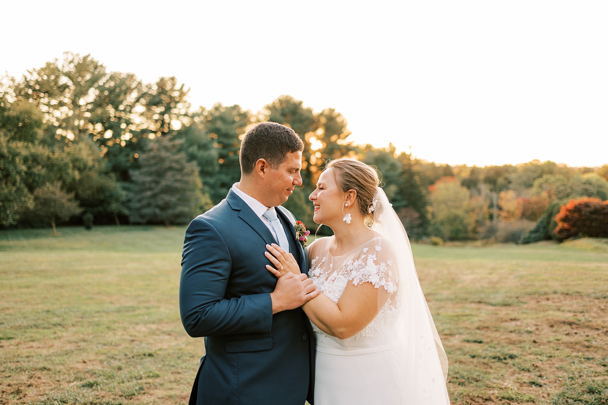 bride and groom hold hands at sunset in front of trees at Greenville Country Club