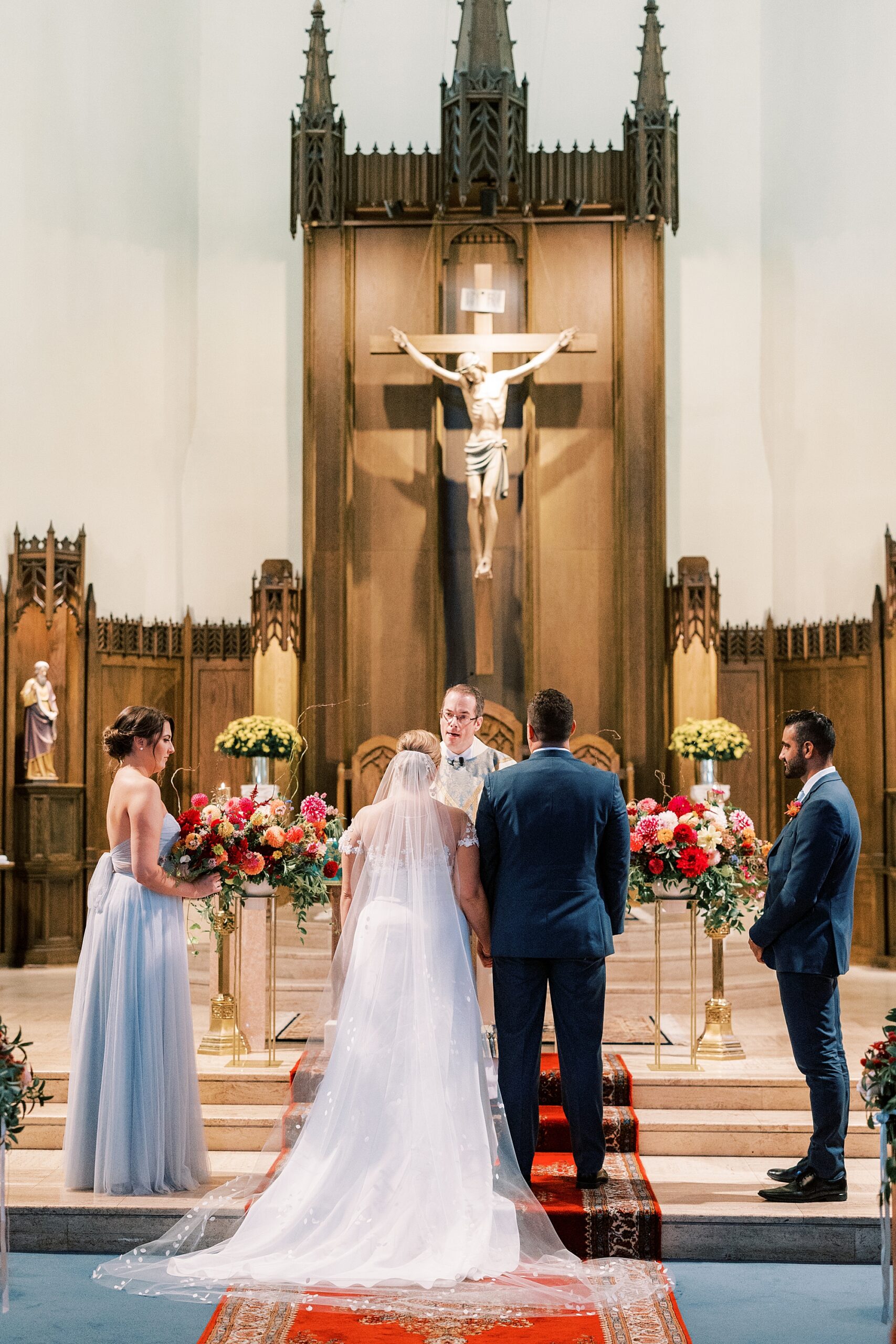 bride and groom stand at alter with bridal party at St. Ann’s Roman Catholic Church