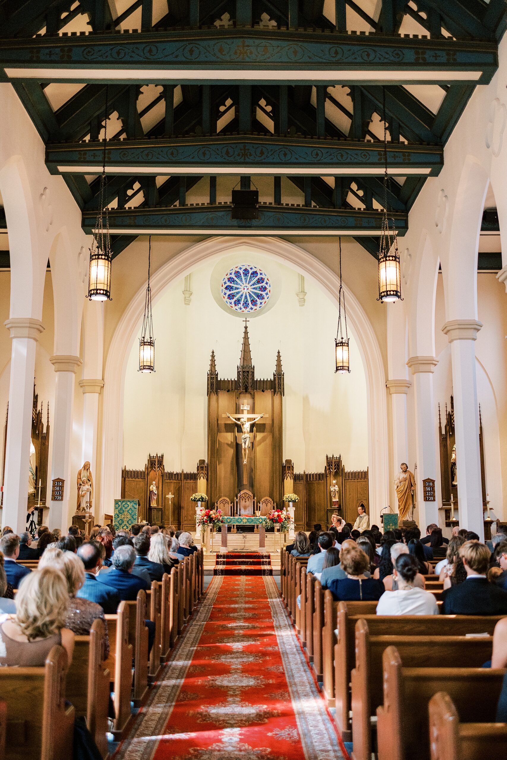 guests wait in pews at St. Ann’s Roman Catholic Church