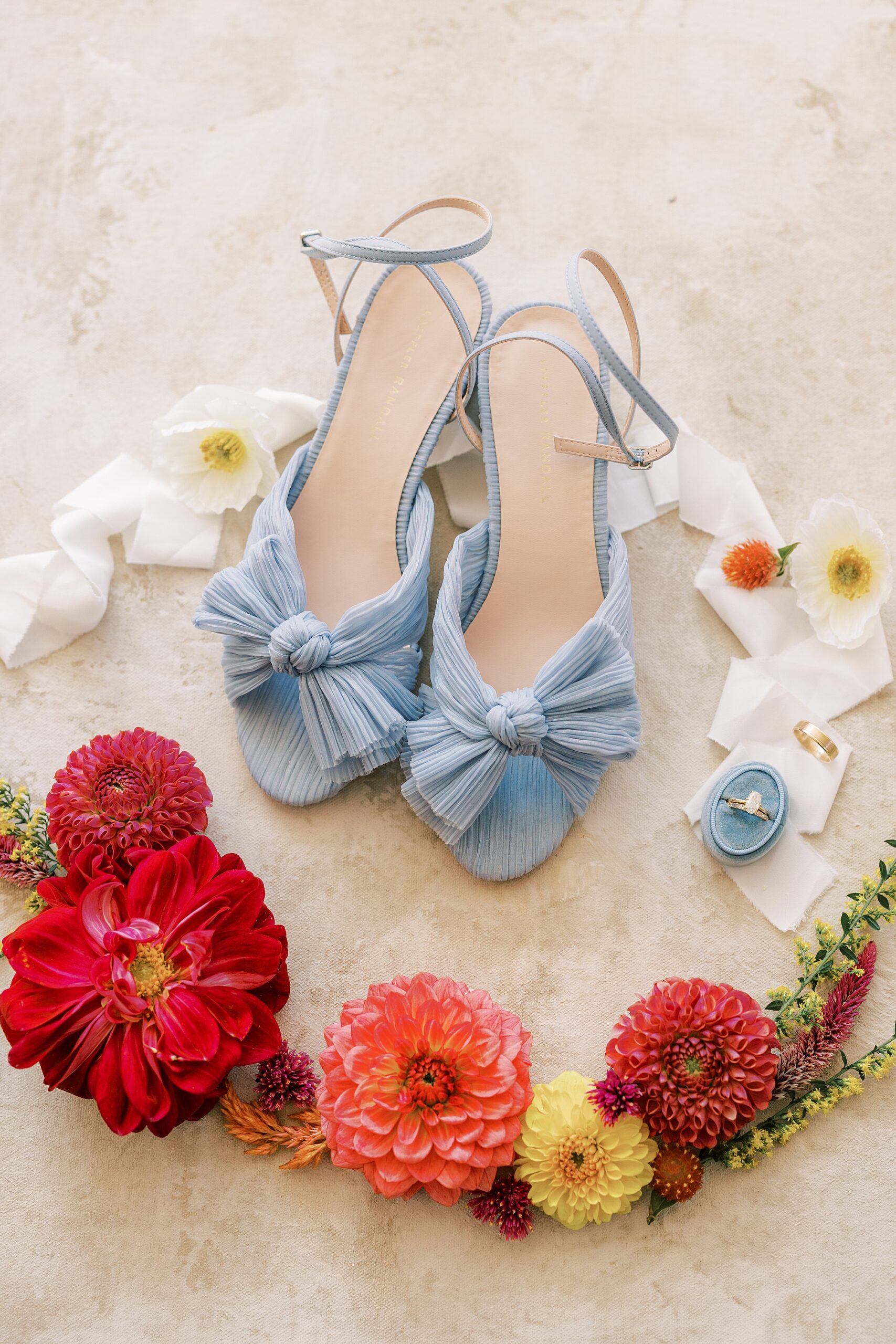 bride's blue shoes rests with pink and red flowers 