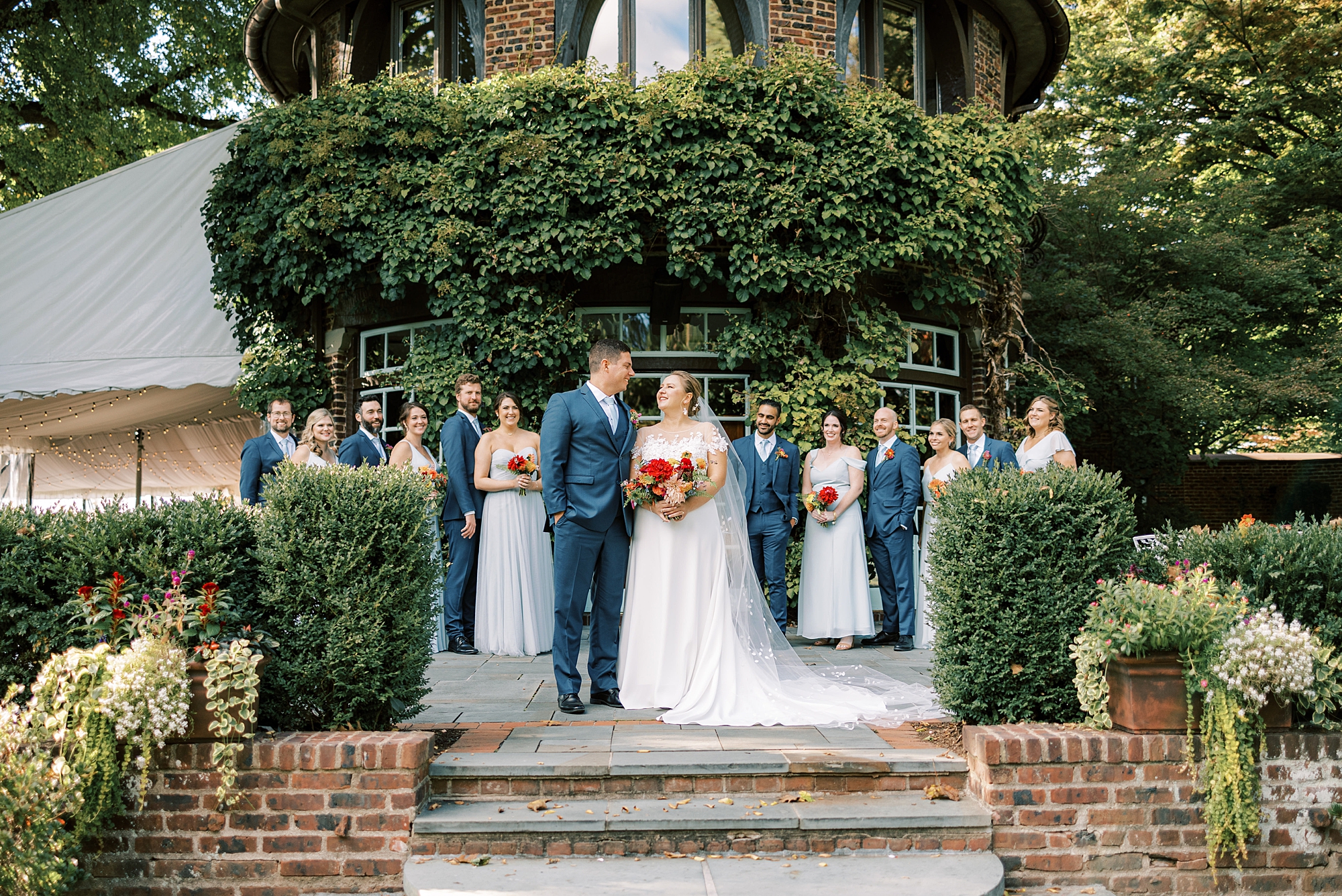 bride and groom stand on steps at Greenville Country Club with wedding party around them 