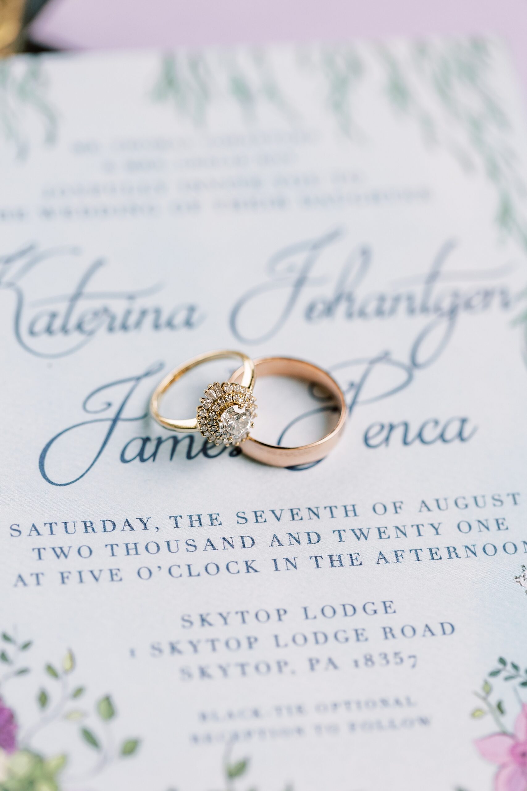 wedding rings rest on blue script for invitations 