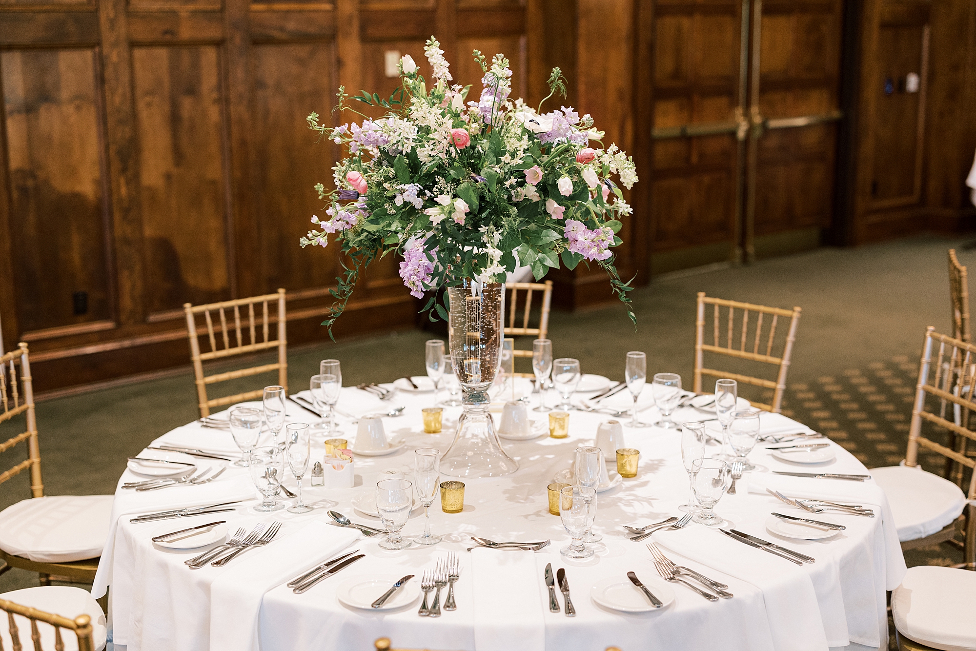wedding reception with pastel flower centerpiece and gold candle holders 