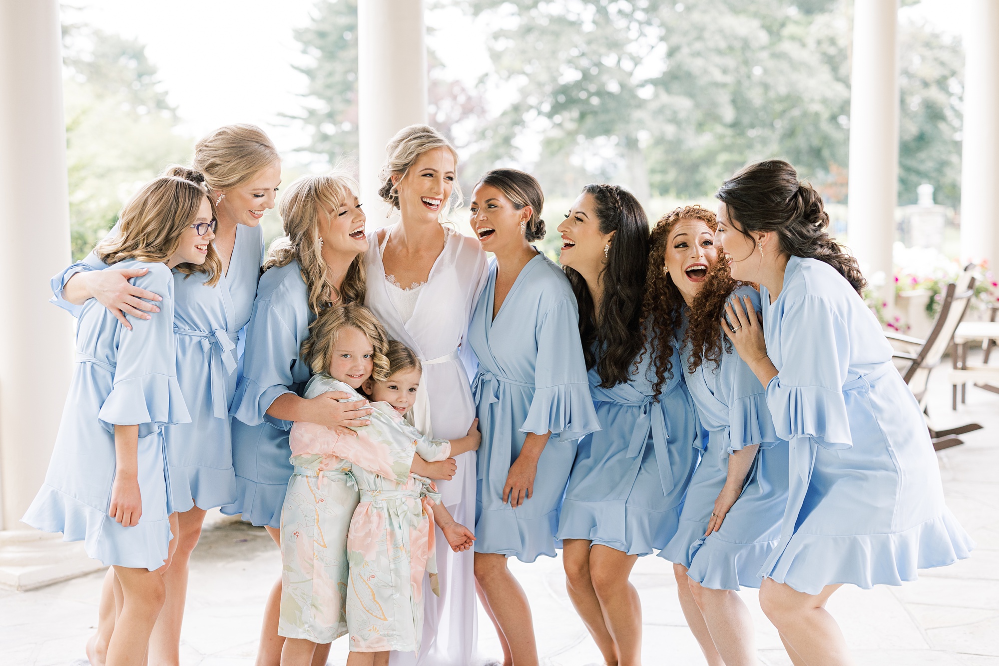 bride hugs bridesmaids in pastel blue robes at Skytop Lodge