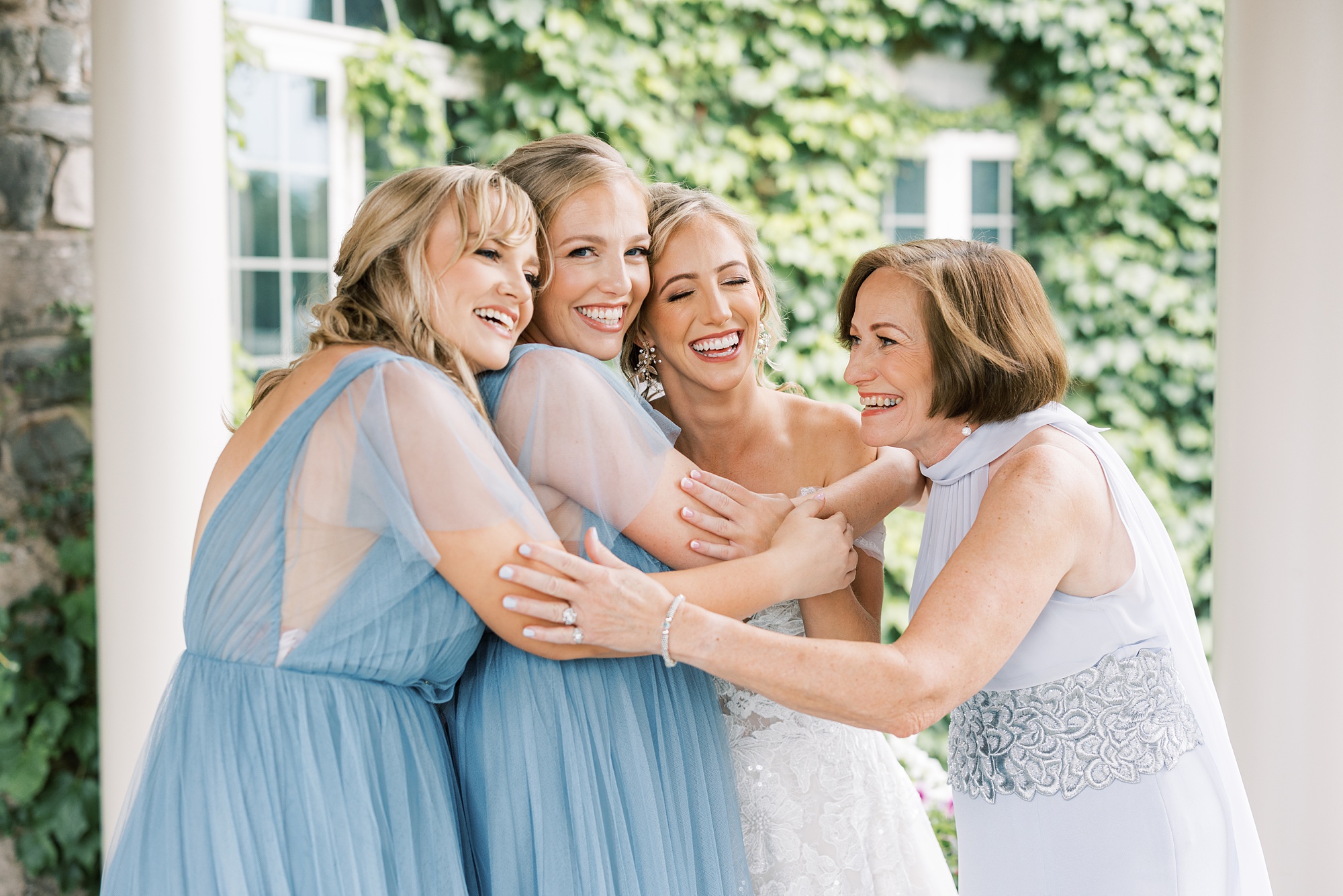 bride laughs with sisters and mom under awning at Skytop Lodge