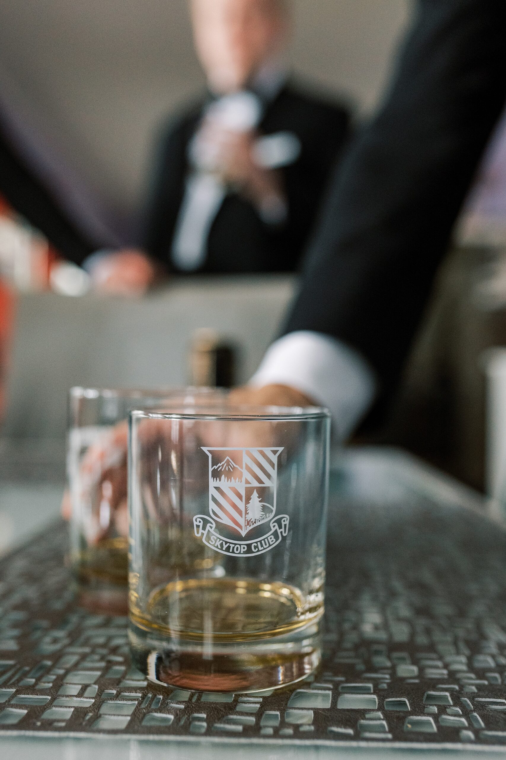 groom holds glass from Skytop Club