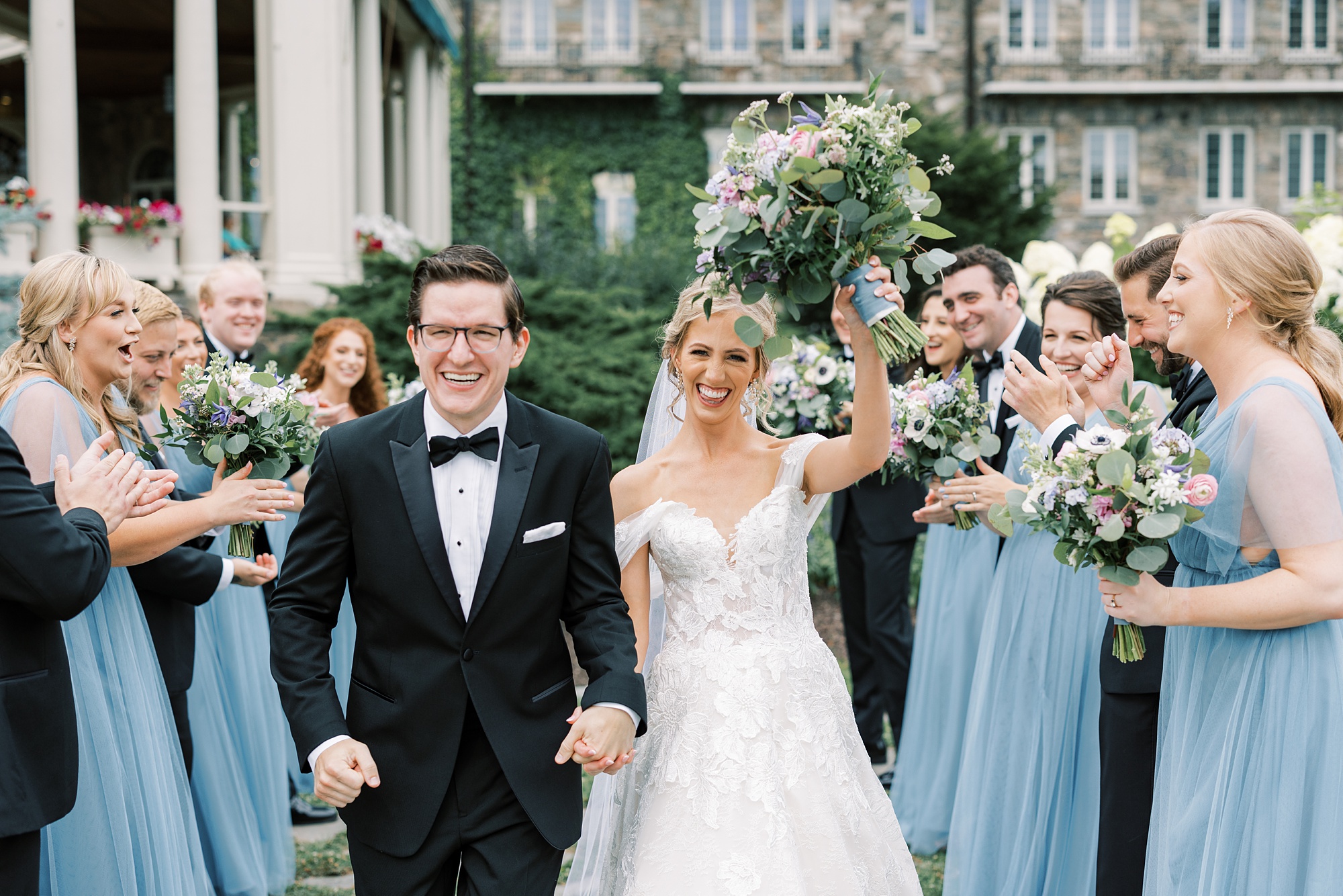 newlyweds cheer and walk between bridesmaids and groomsmen