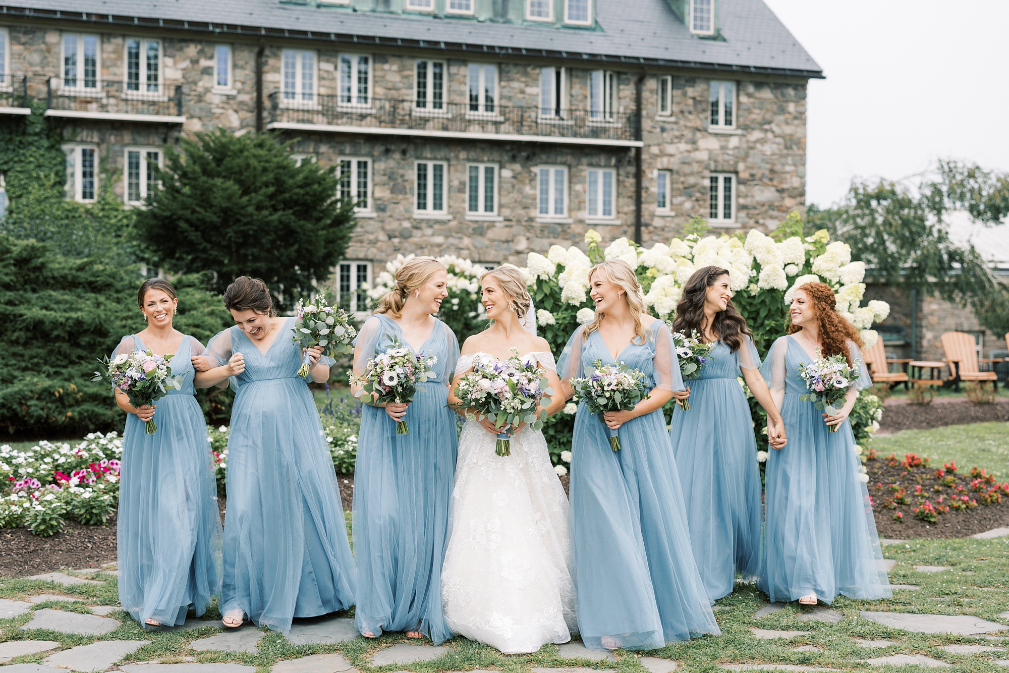 bride stands with bridesmaids in light blue dresses