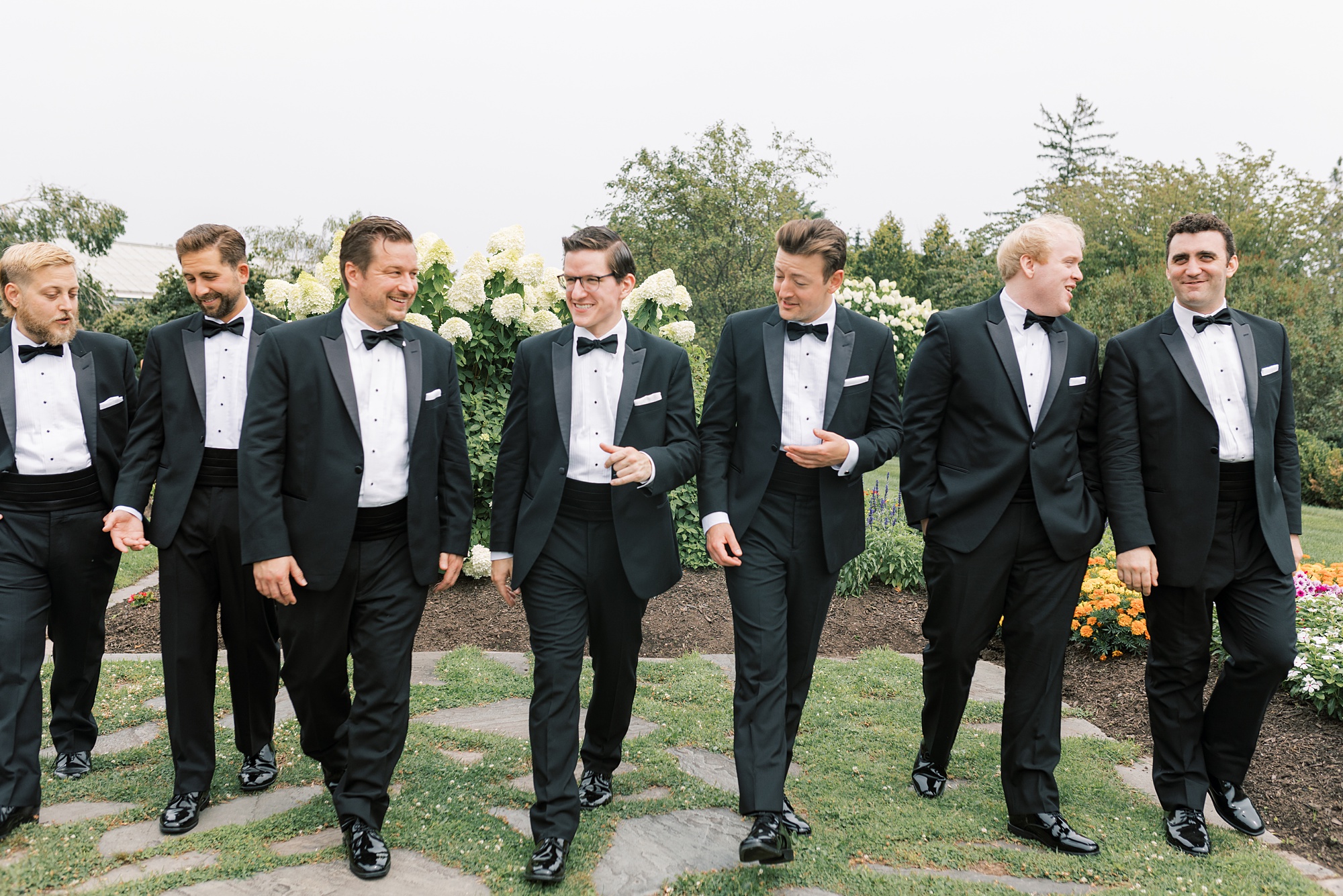groom stands with groomsmen in black suits