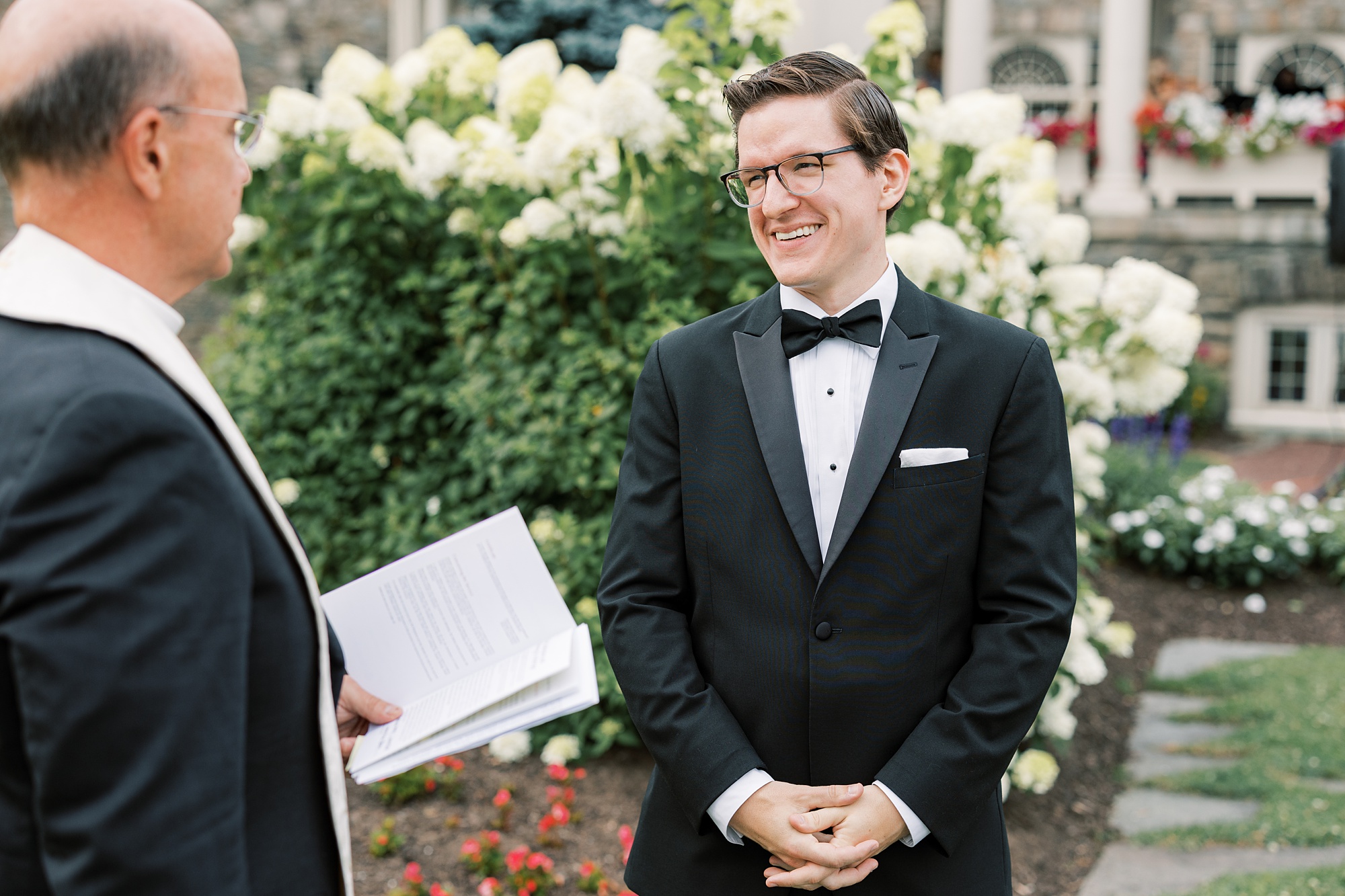 groom smiles with officiant before wedding ceremony on lawn at Skytop Lodge