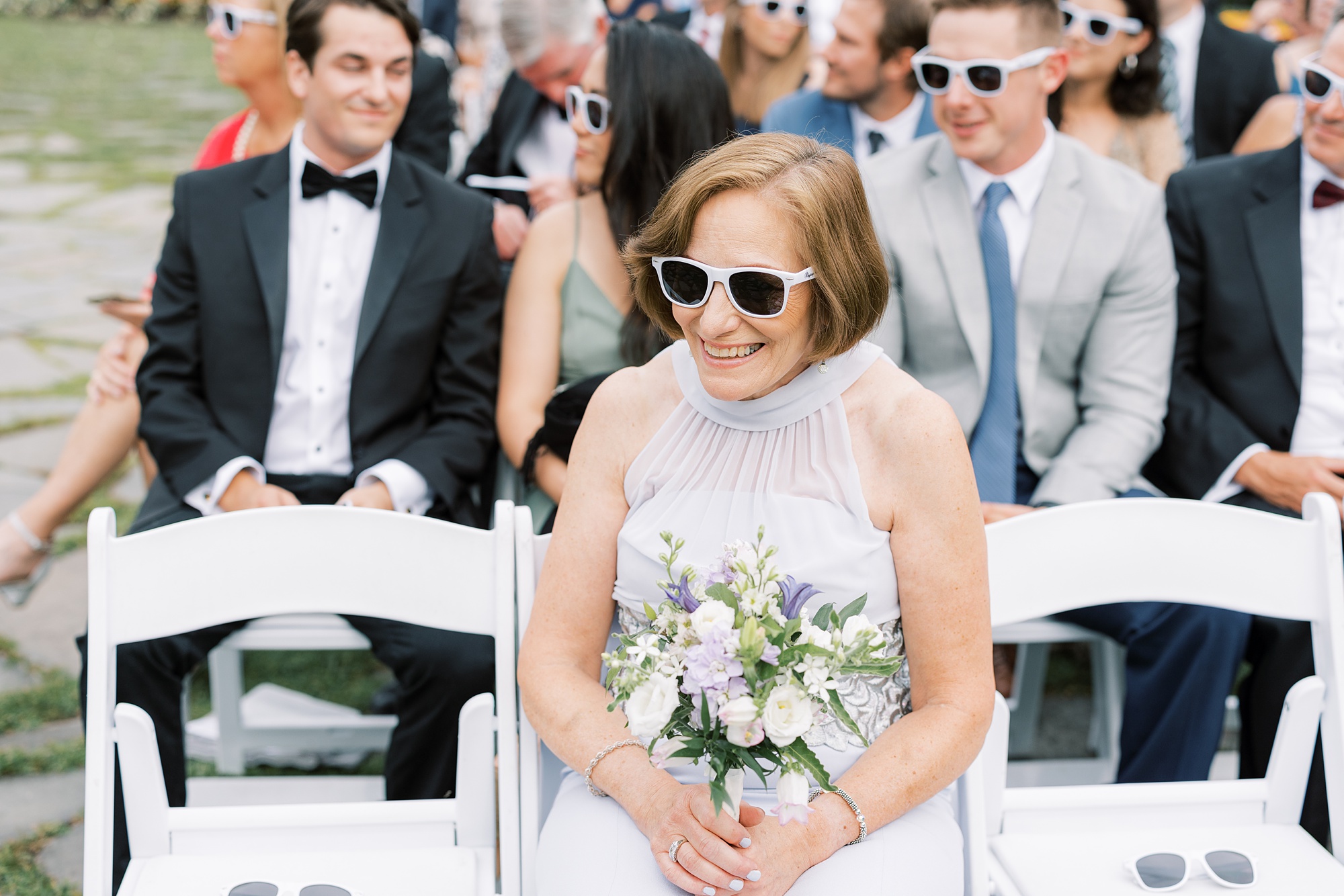 mom in sunglasses holds white flowers 