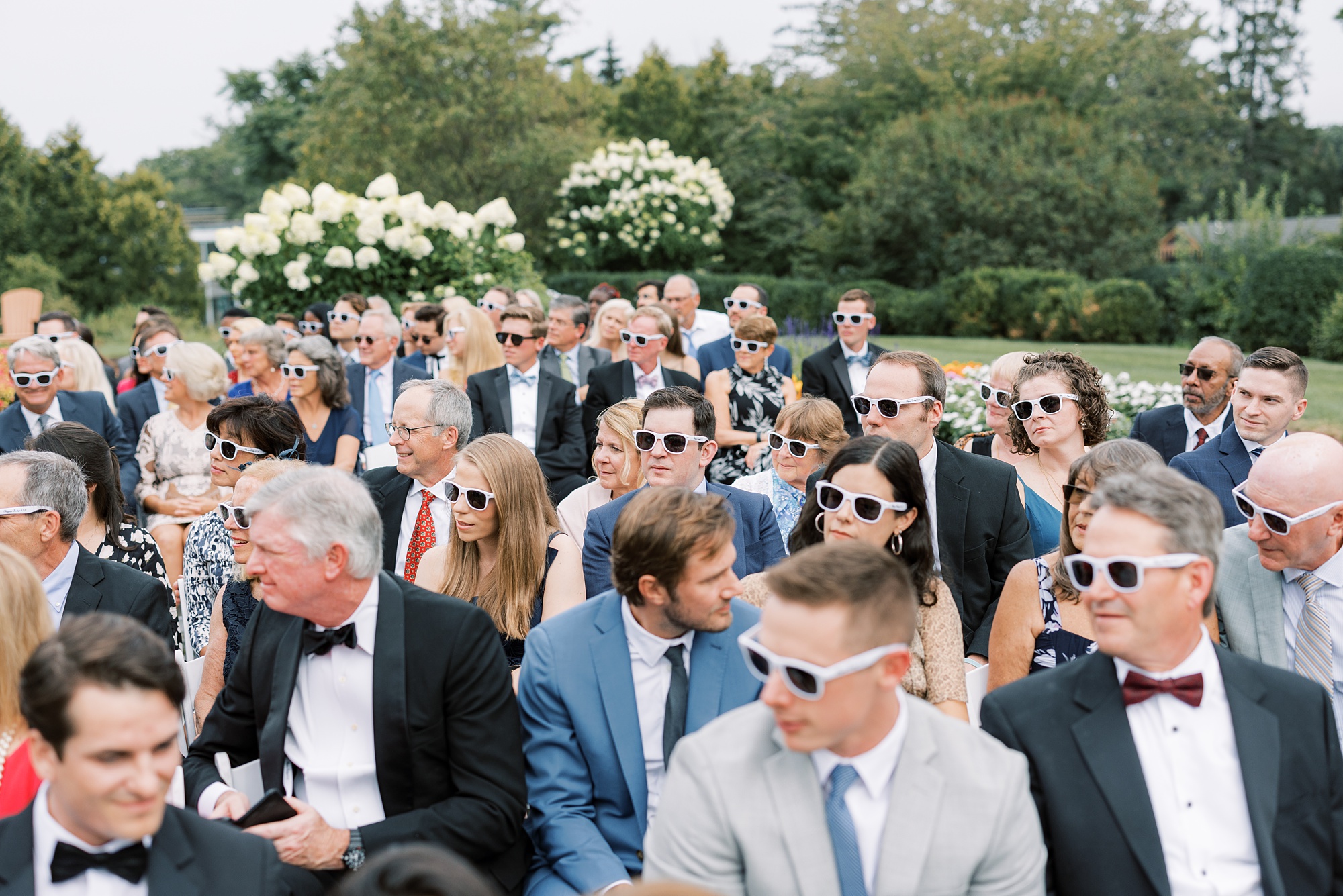 guests wear sunglasses during wedding ceremony on lawn at Skytop Lodge
