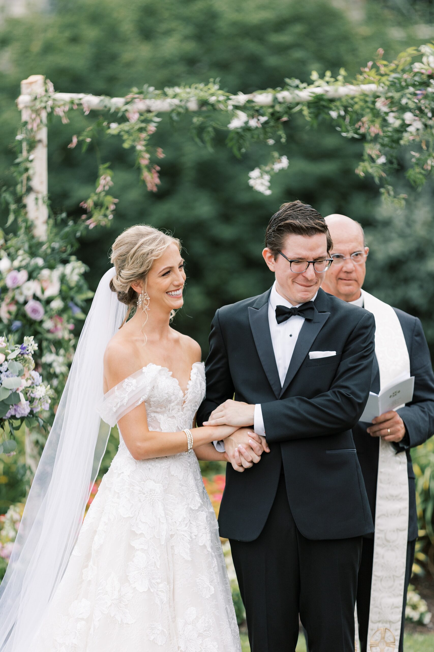 bride and groom hold hands looking at guests