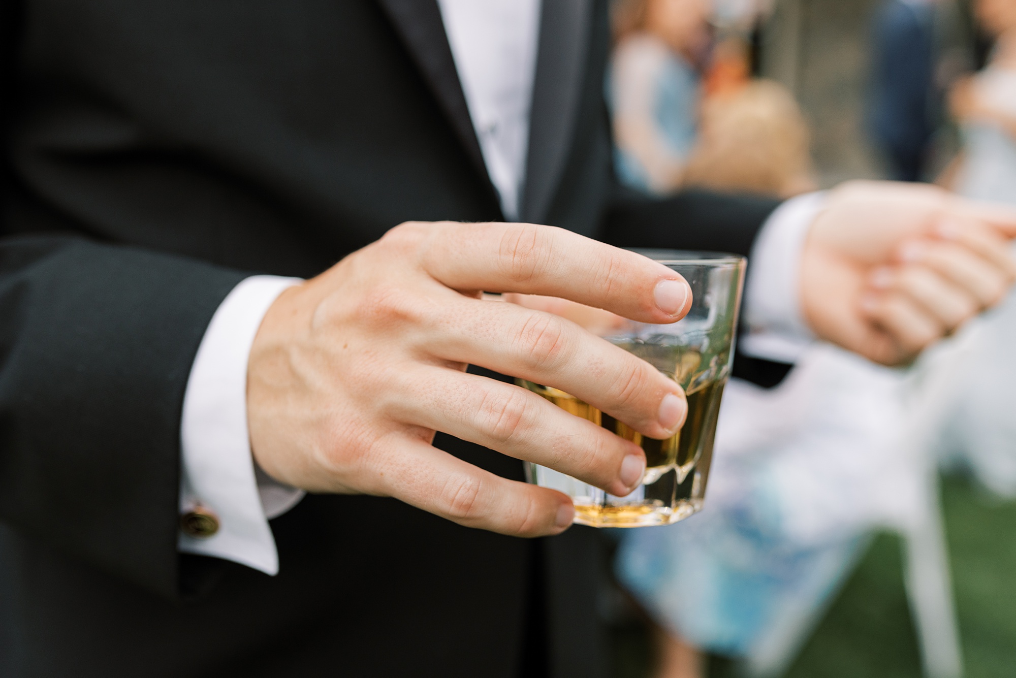 groom holds drink during cocktail hour 