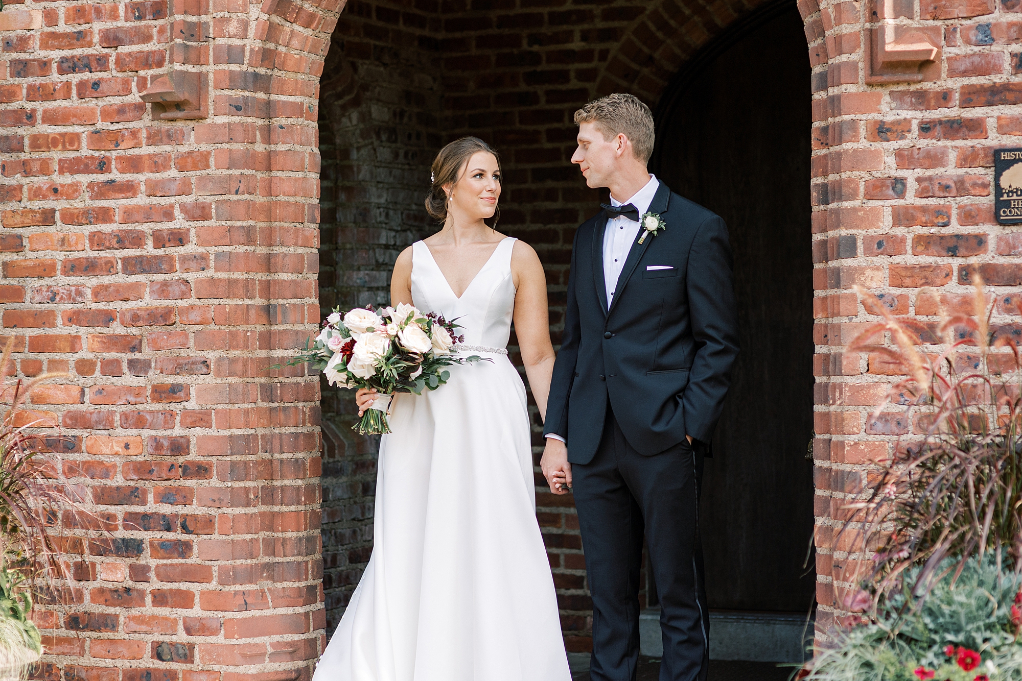bride and groom hold hands in brick doorway at Aldie Mansion