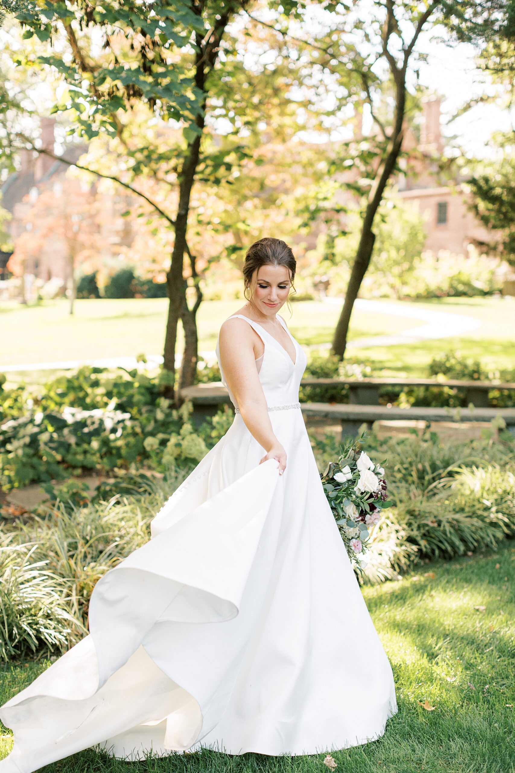 bride in classic wedding gown twirls on lawn at Aldie Mansion