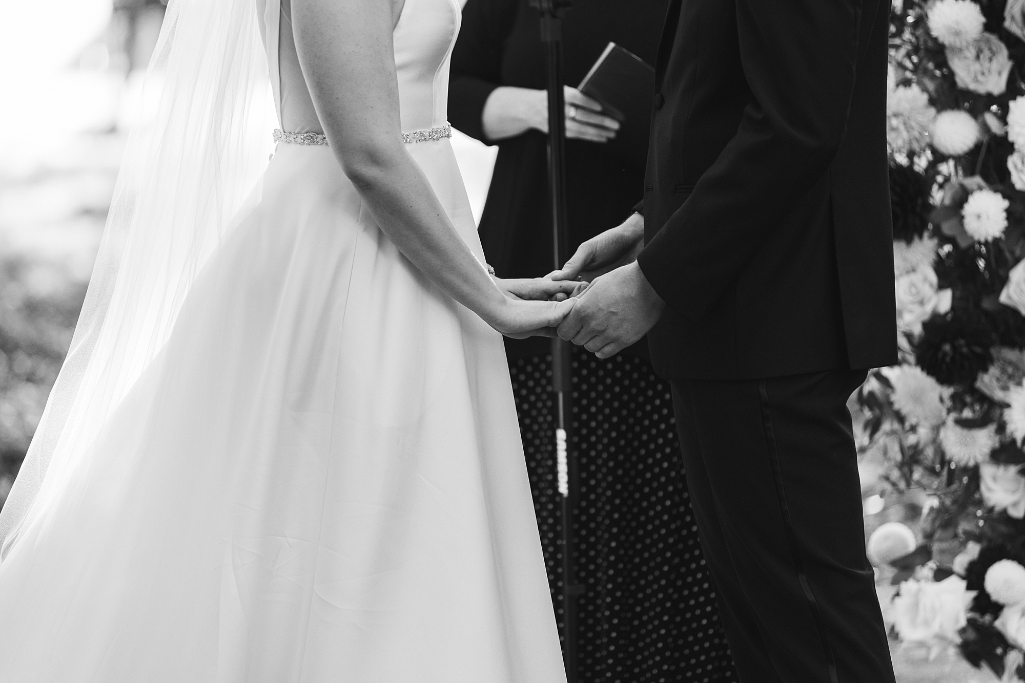 black and white photo of bride and groom holding hands 