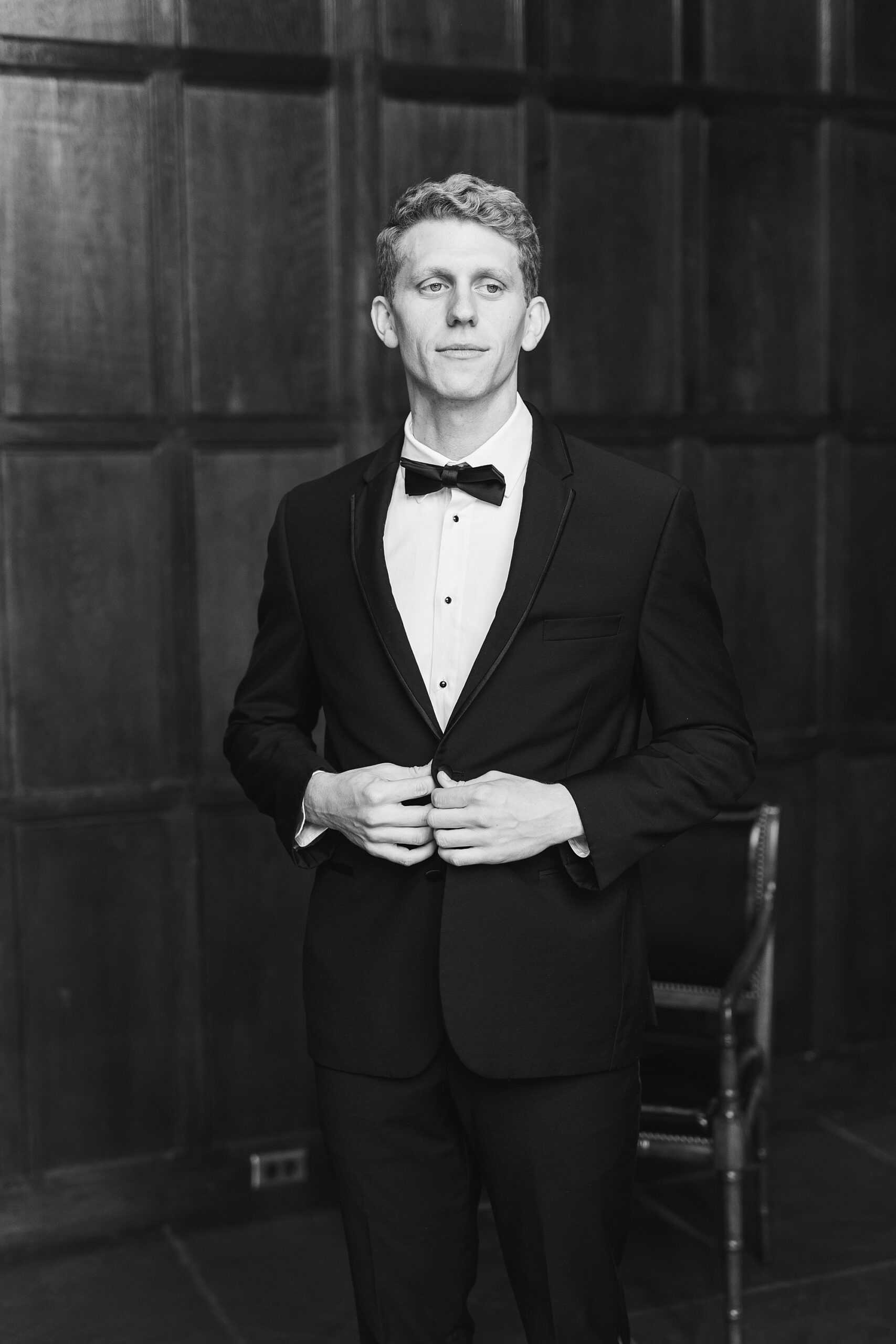groom stands in classic suit in wide paneled wall at Aldie Mansion