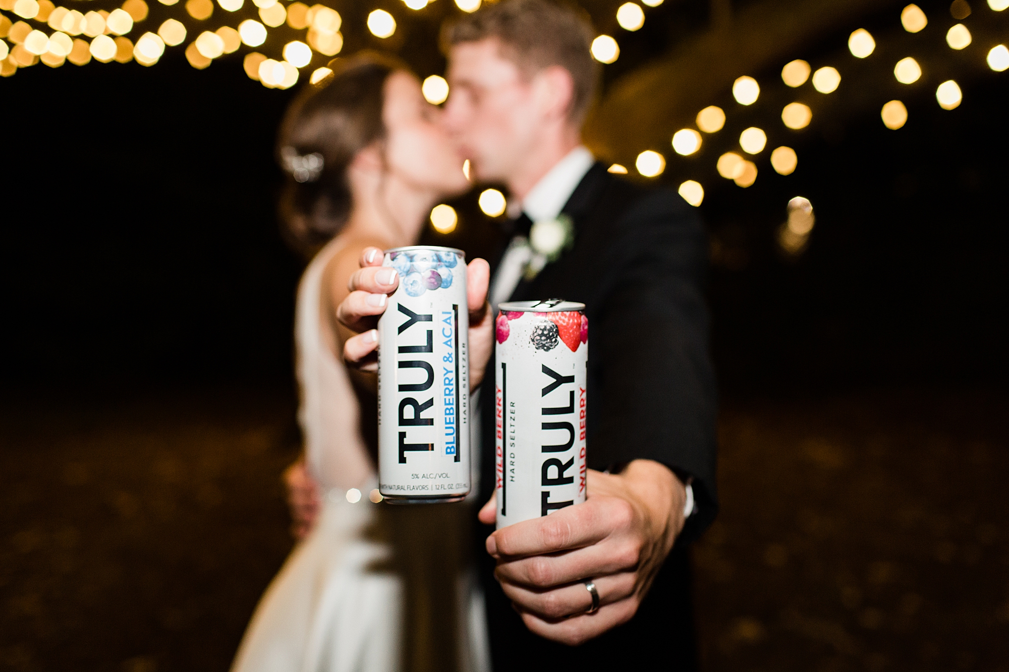 bride and groom kiss holding out Truly drinks