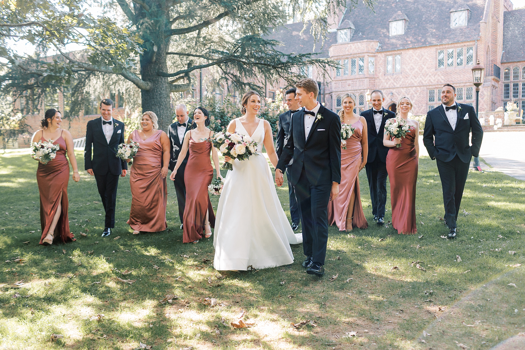 bride and groom hold hands walking in front of wedding party at Aldie Mansion