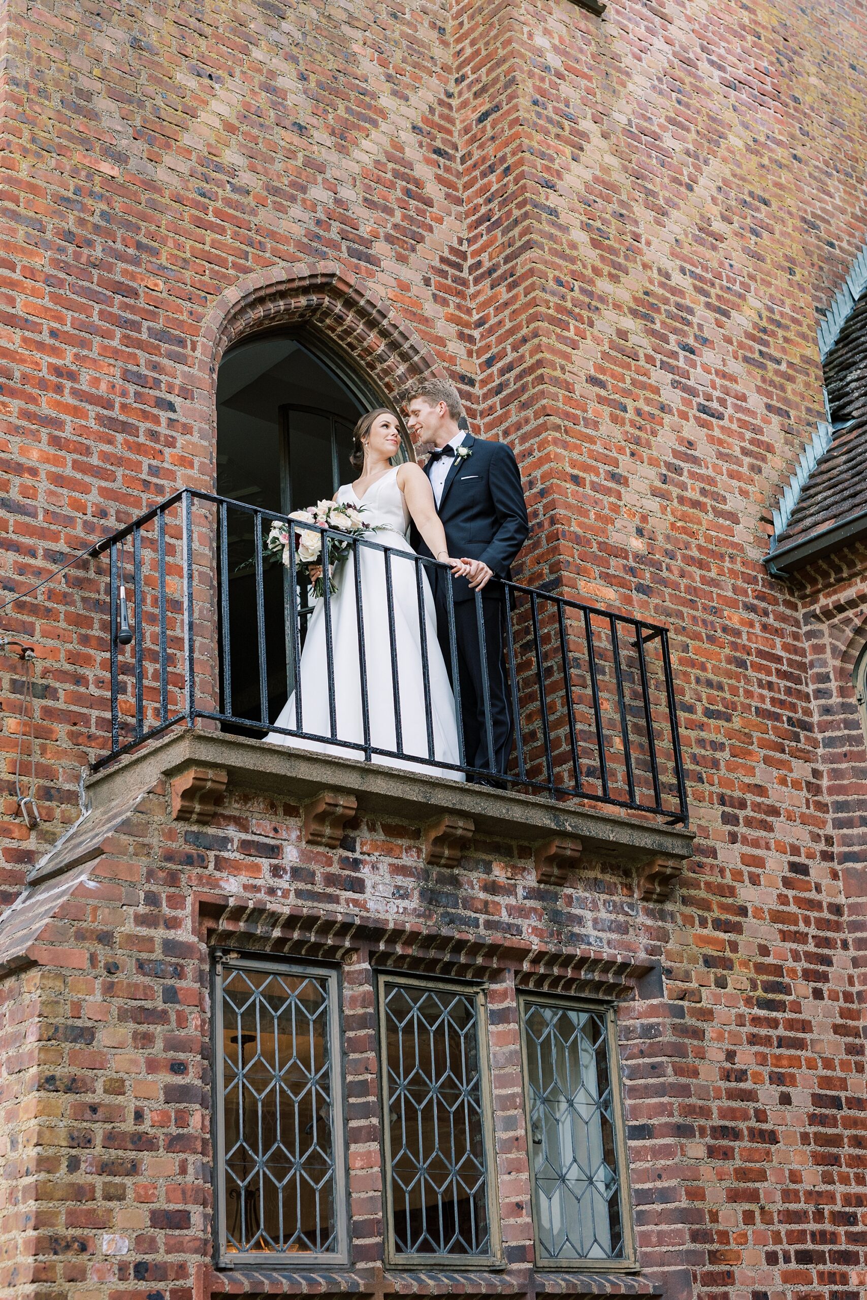 bride and groom stand on balcony over courtyard at Aldie Mansion