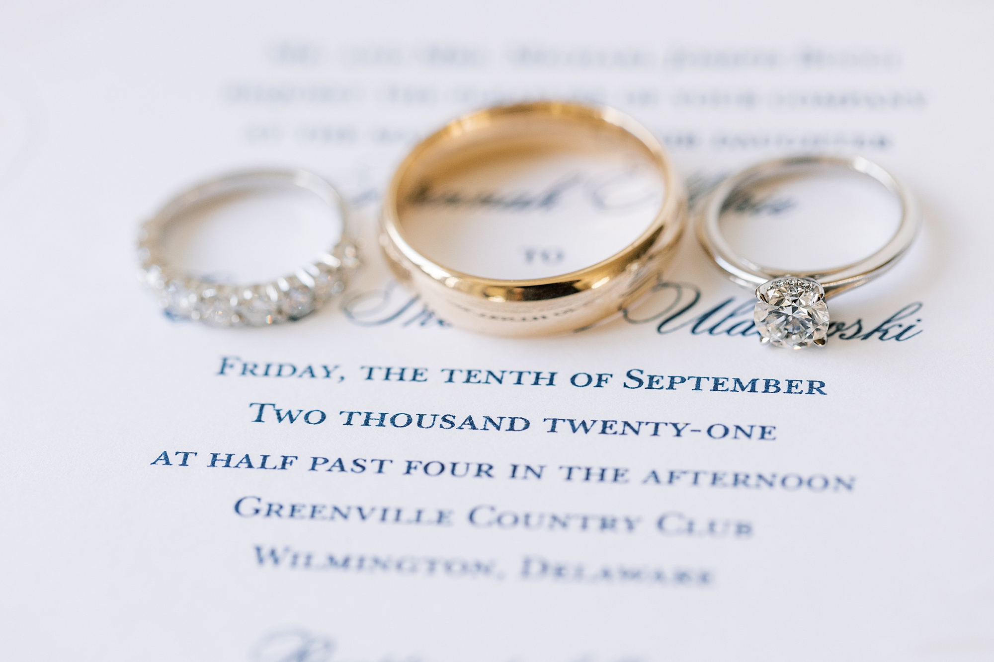 wedding rings lay on blue script on invitations
