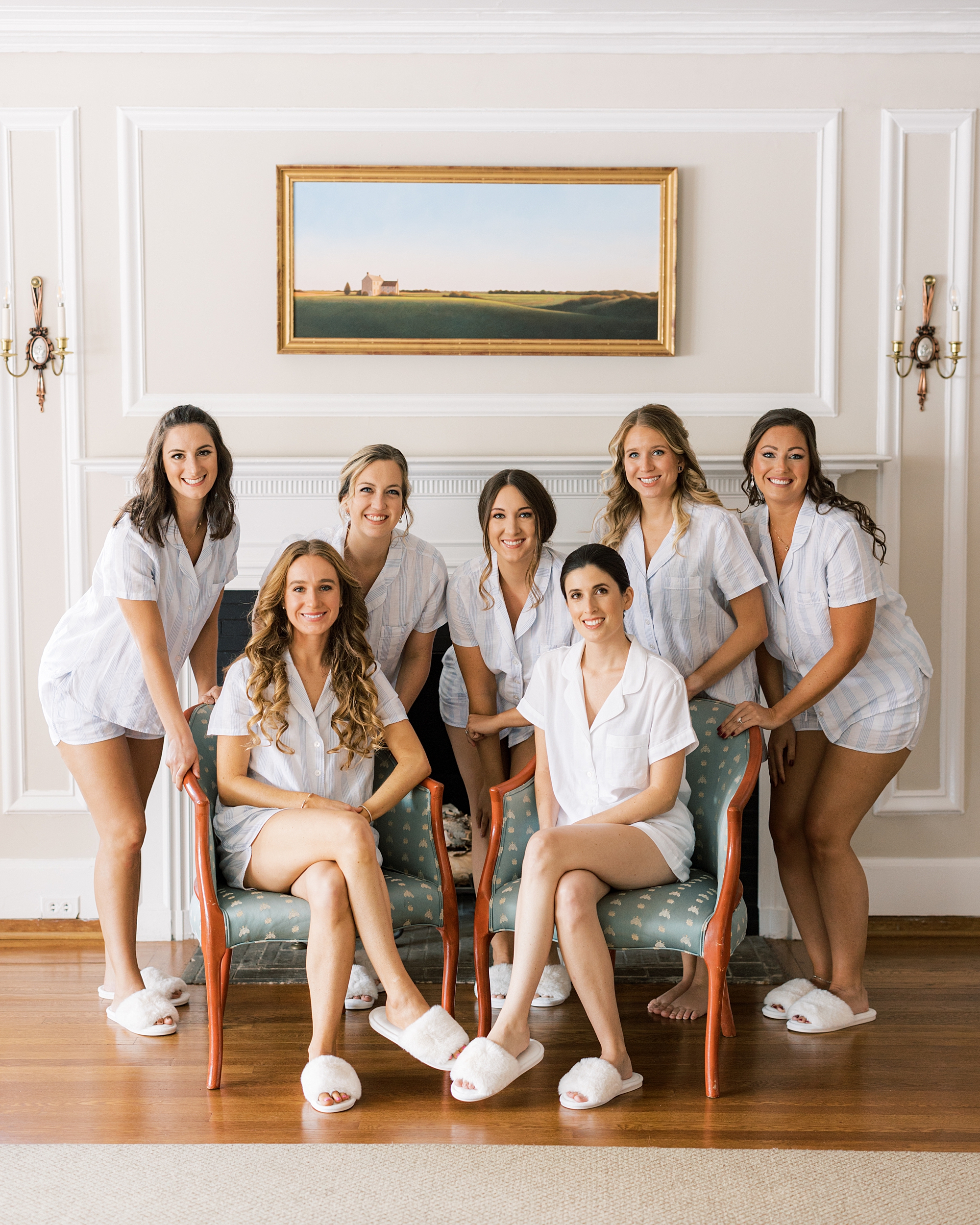 bride poses with bridesmaids under painting inside Greenville Country Club