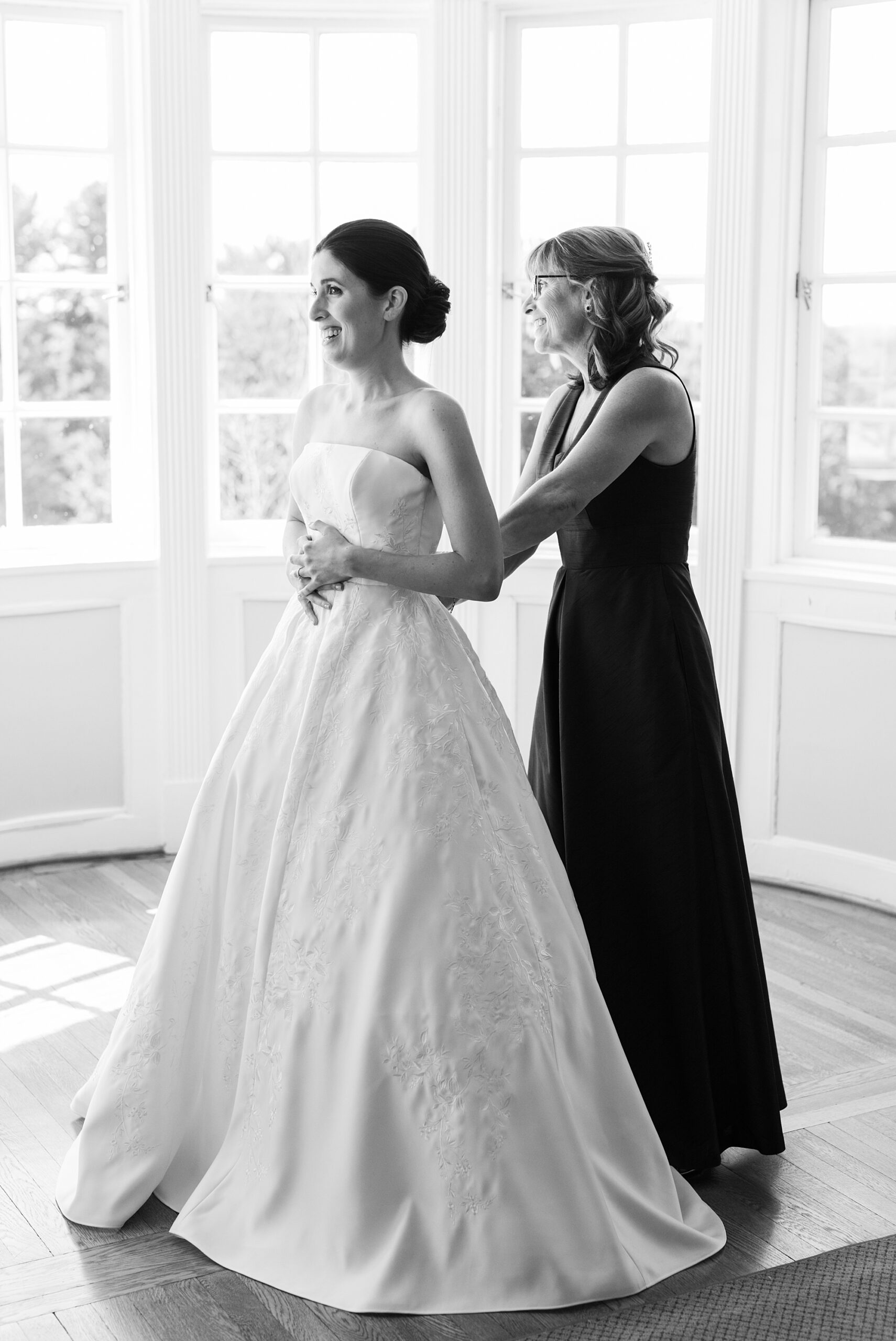 mother helps bride into wedding dress at Greenville Country Club