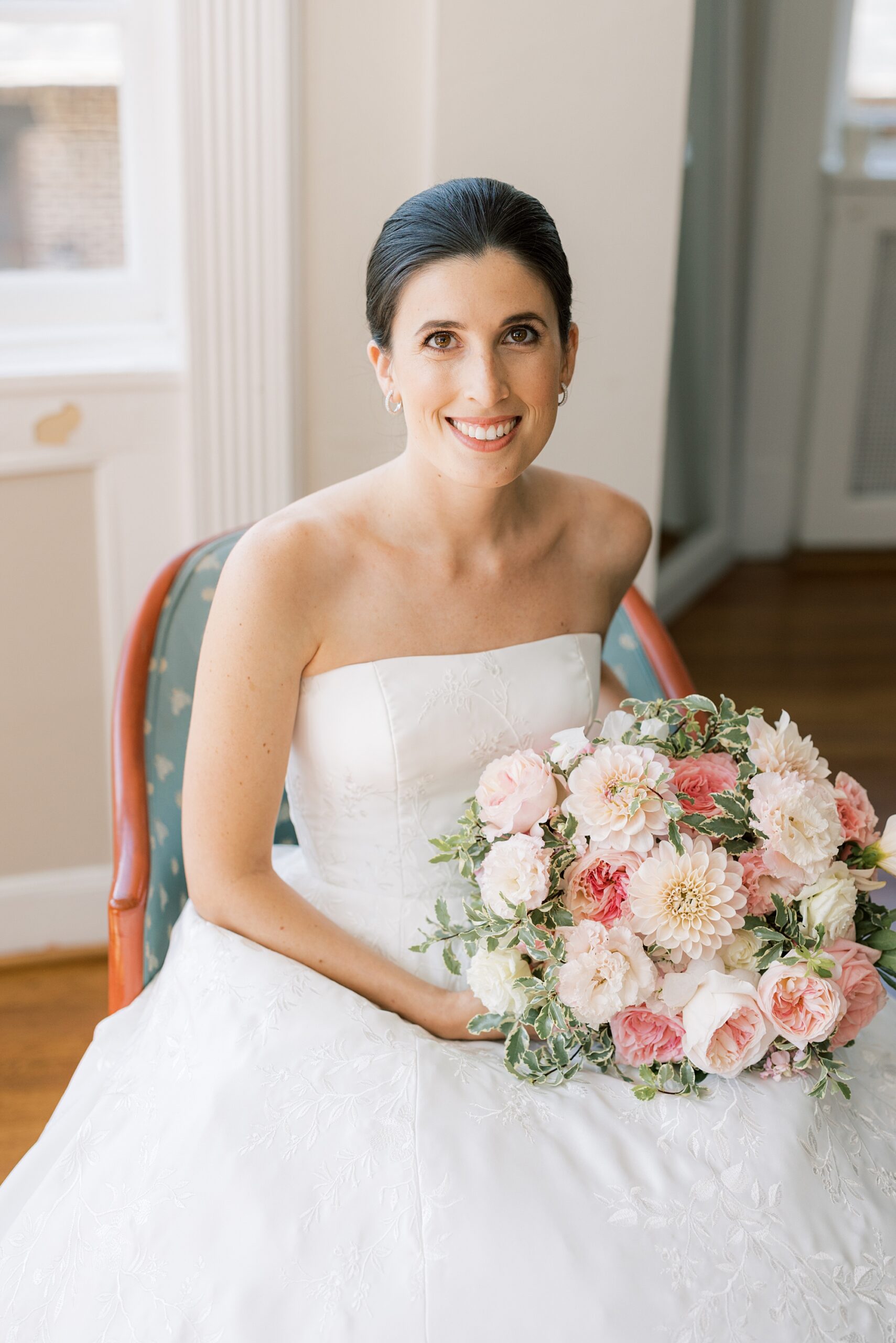 bride smiles with pink and white bouquet in lap