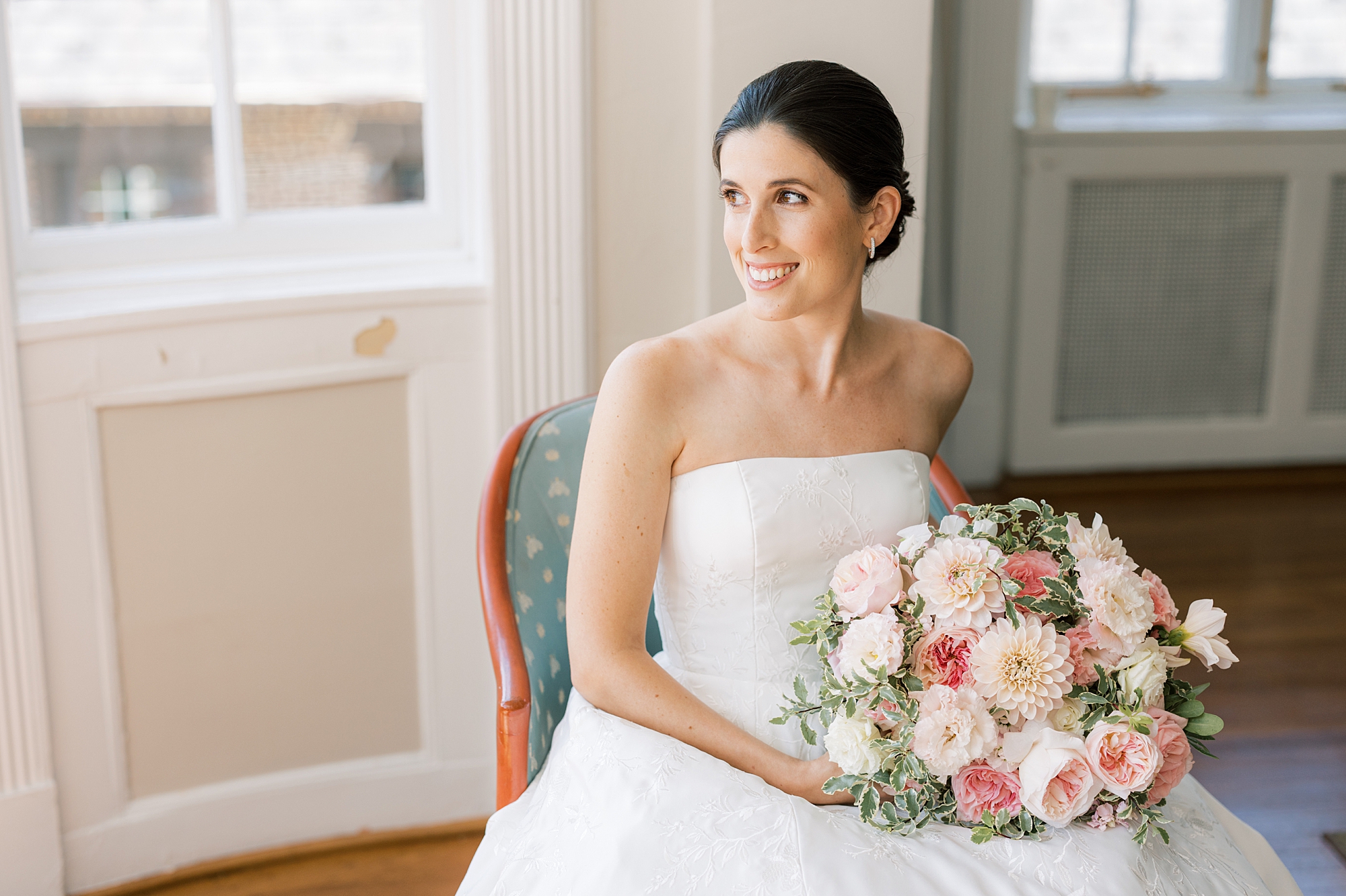bride looks to the side while holding bouquet of pink and white flowers 