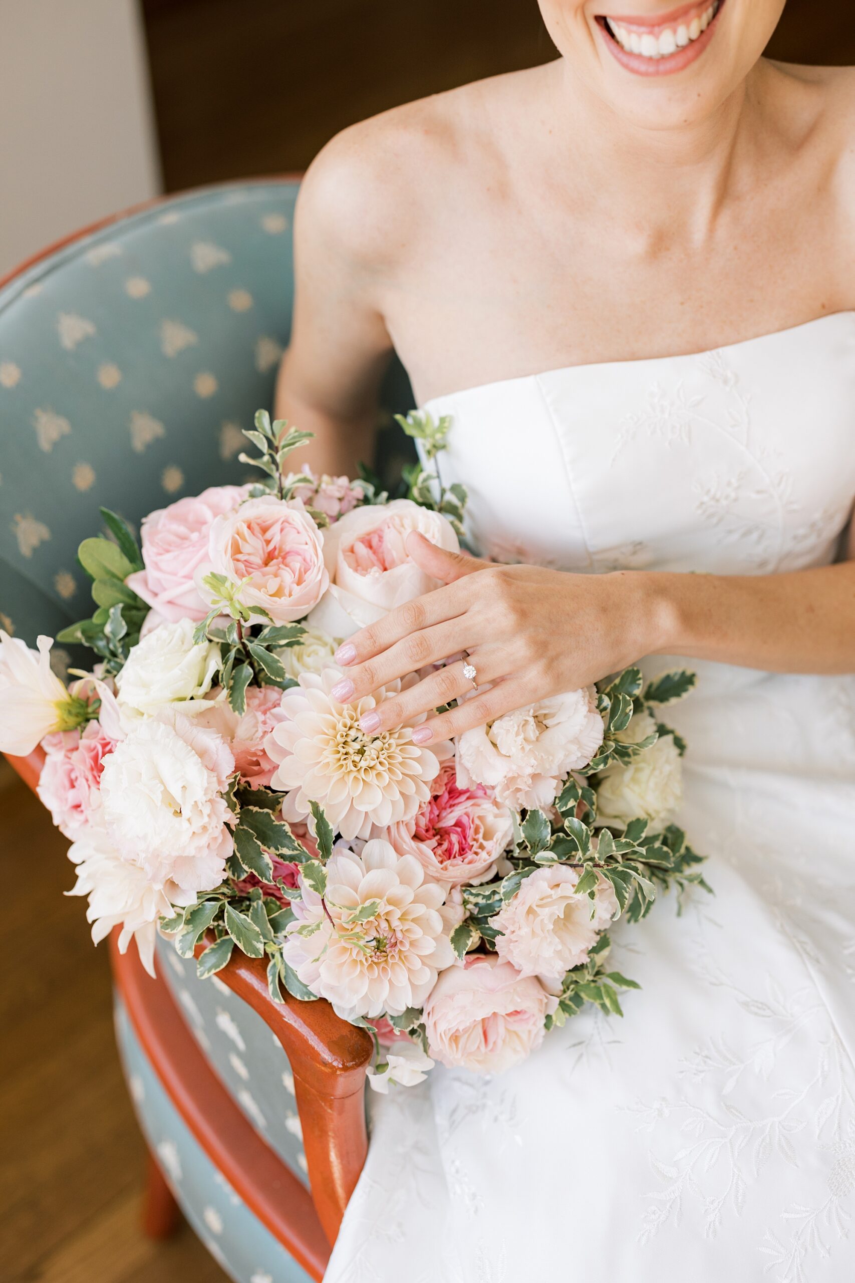 bride lays hand on pink flowers in bouquet 