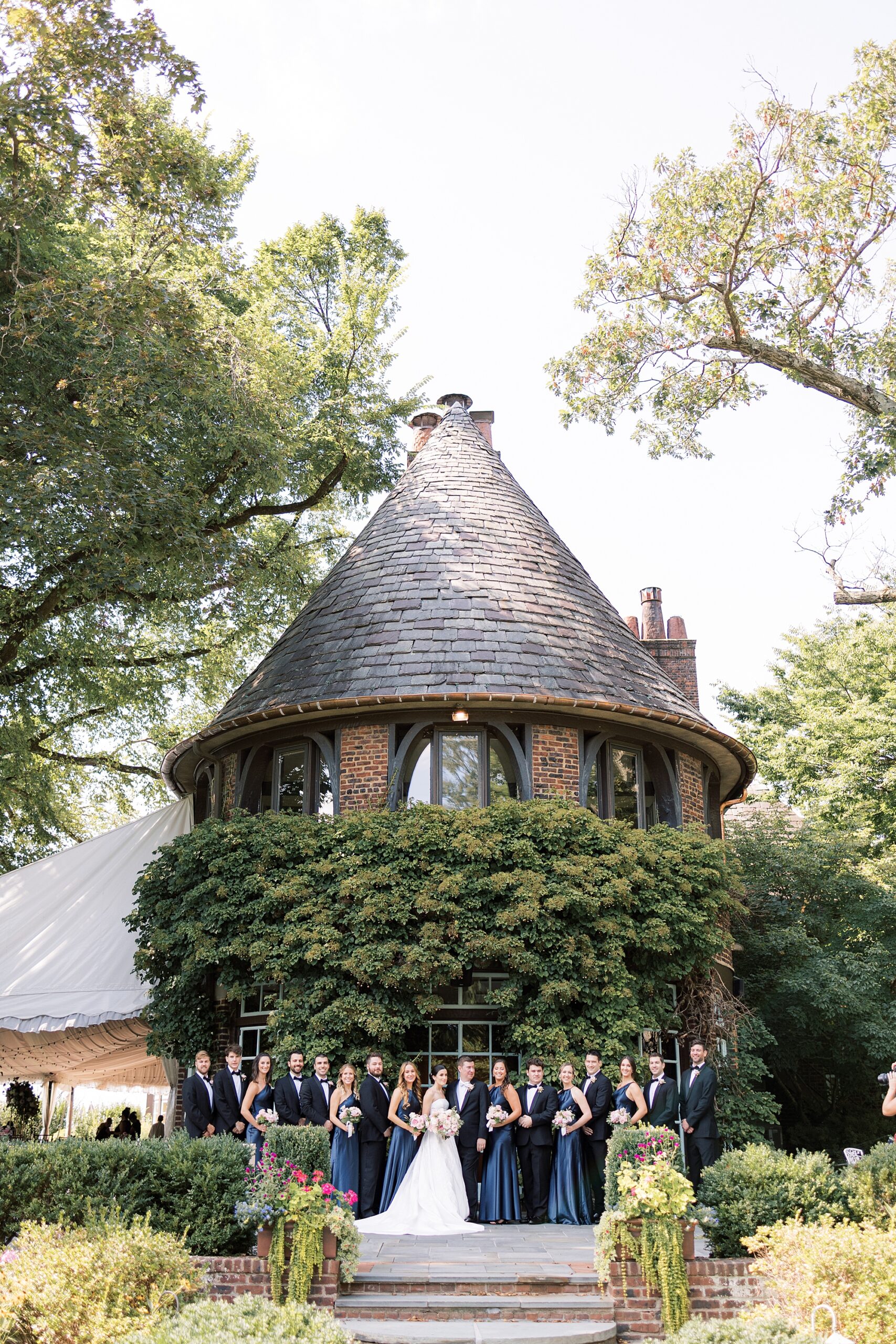 bride poses with bridesmaids in navy gowns by turret at Greenville Country Club