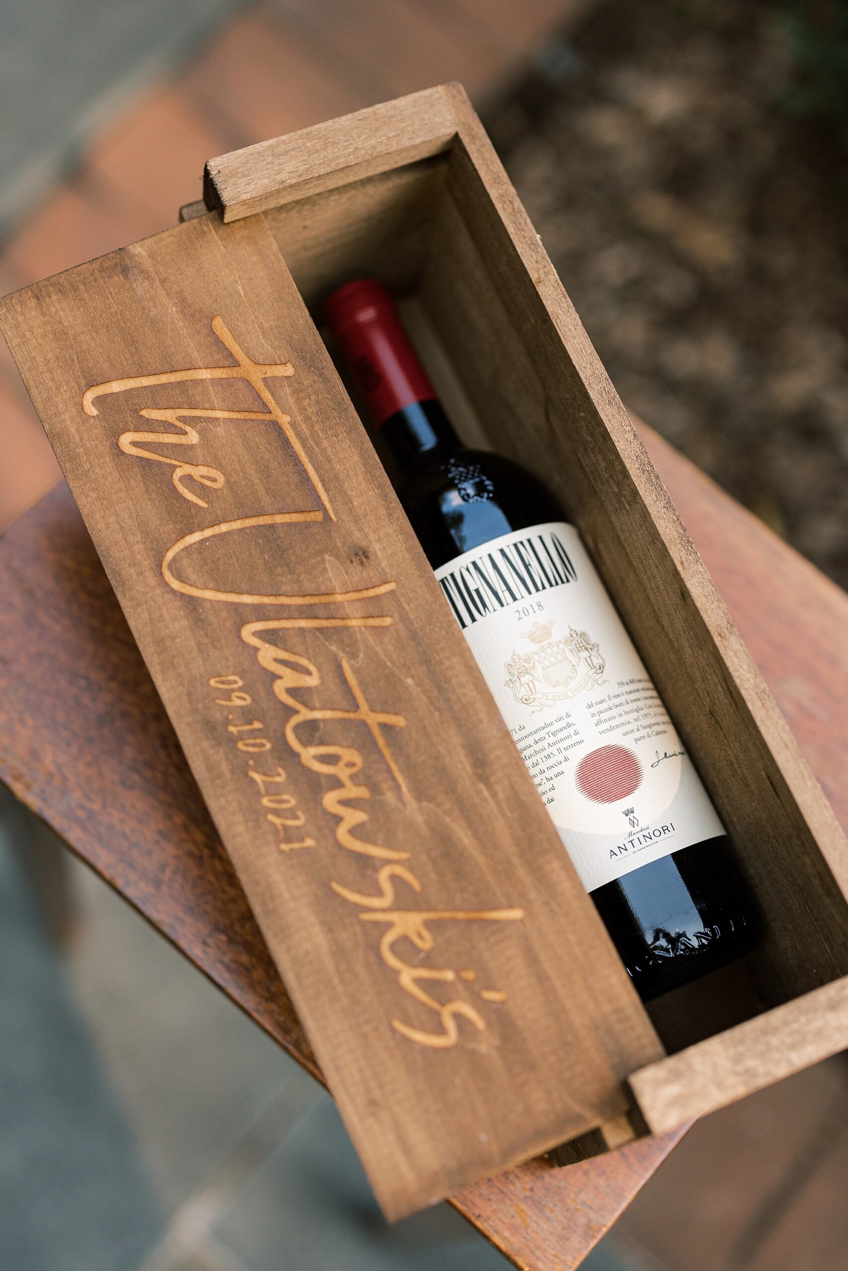 wine bottle lays in wooden box with couple's name on it 