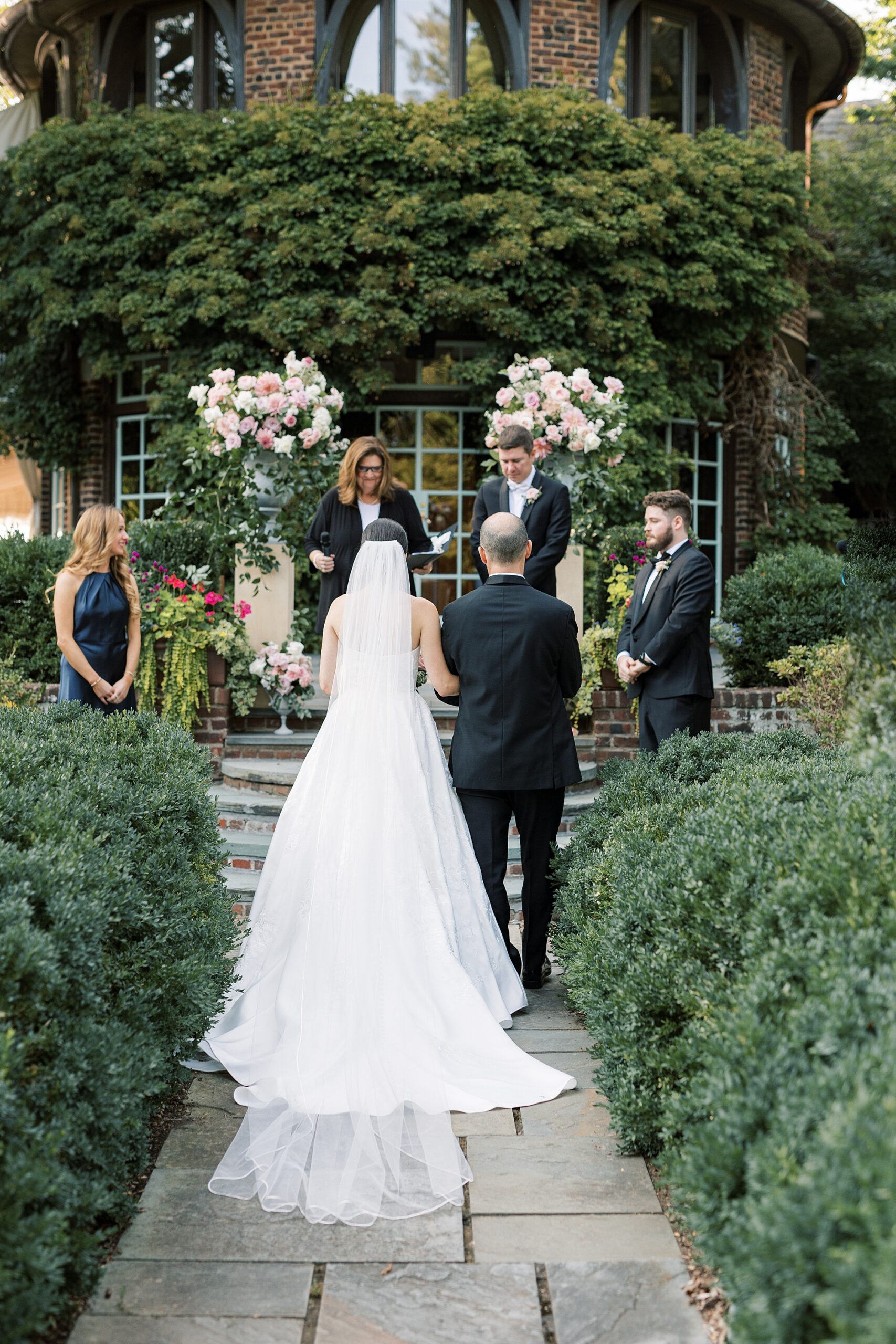 bride walks down aisle with brother in garden at Greenville Country Club