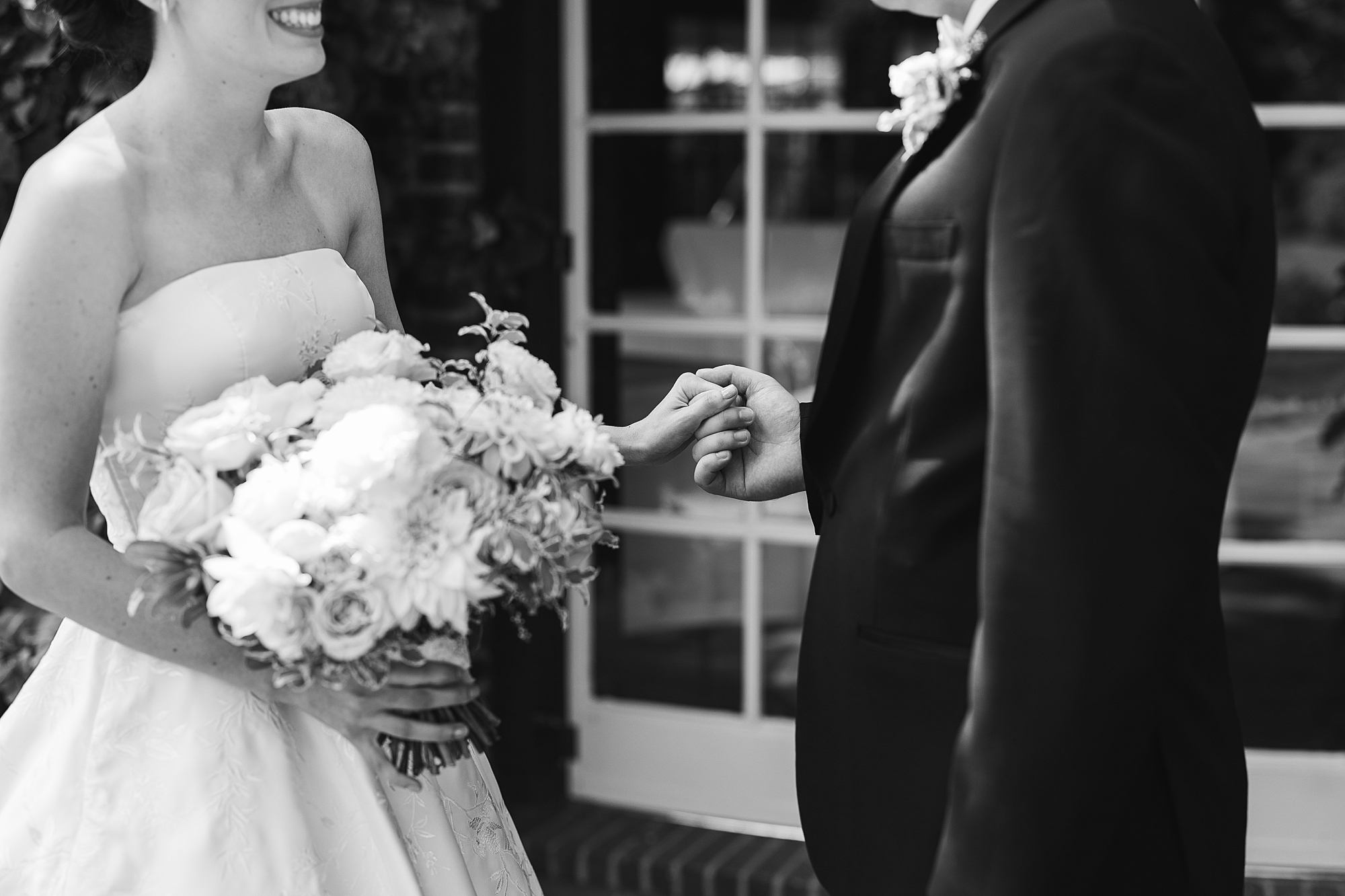 bride and groom hold hands smiling during first look 