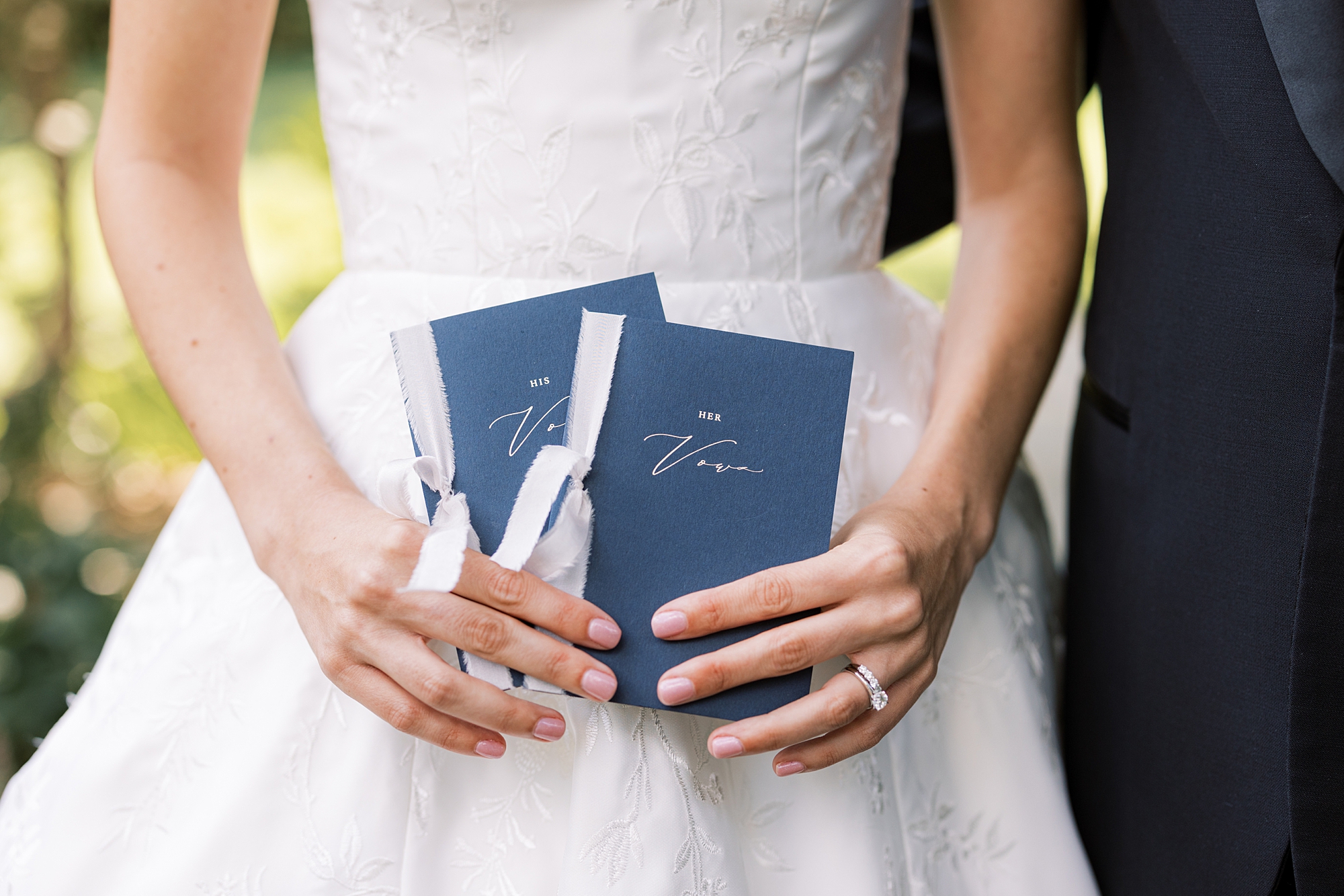 bride holds two navy vow booklets 