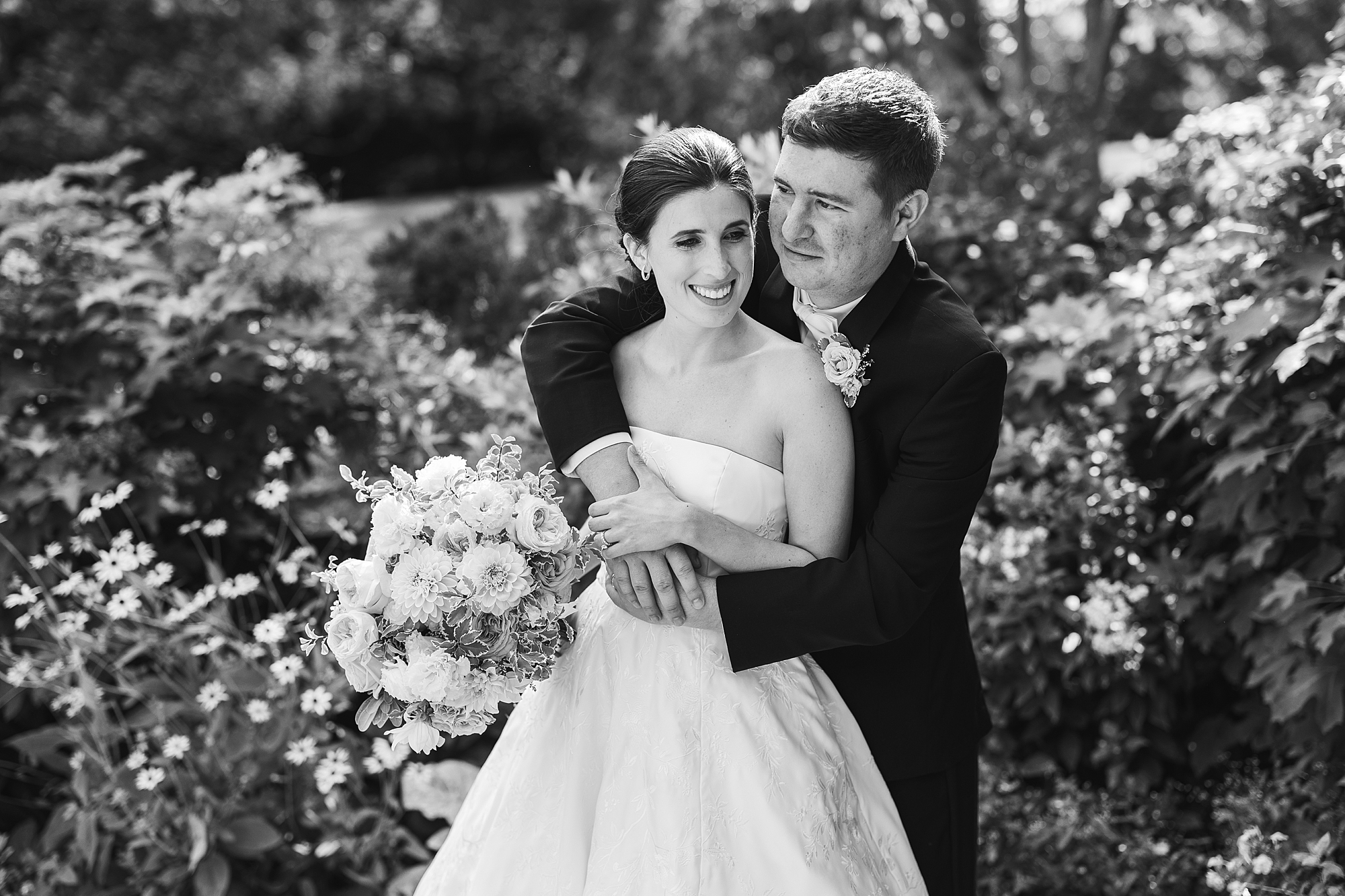 black and white photo of groom holding bride from behind 