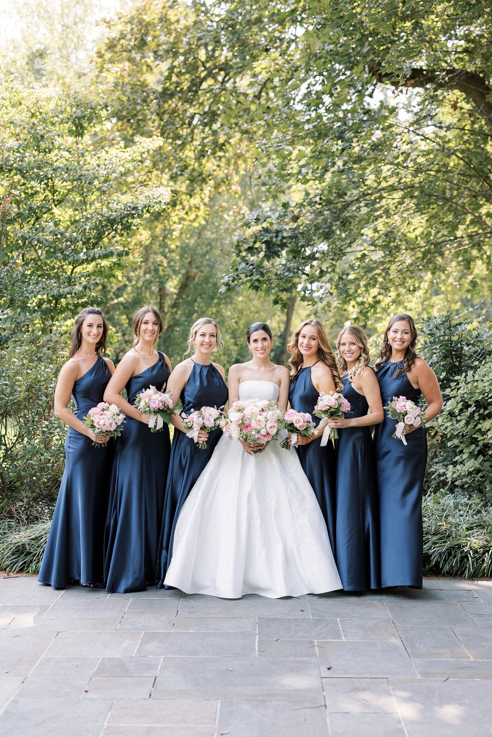 bride stands with bridesmaids in navy gowns at Greenville Country Club
